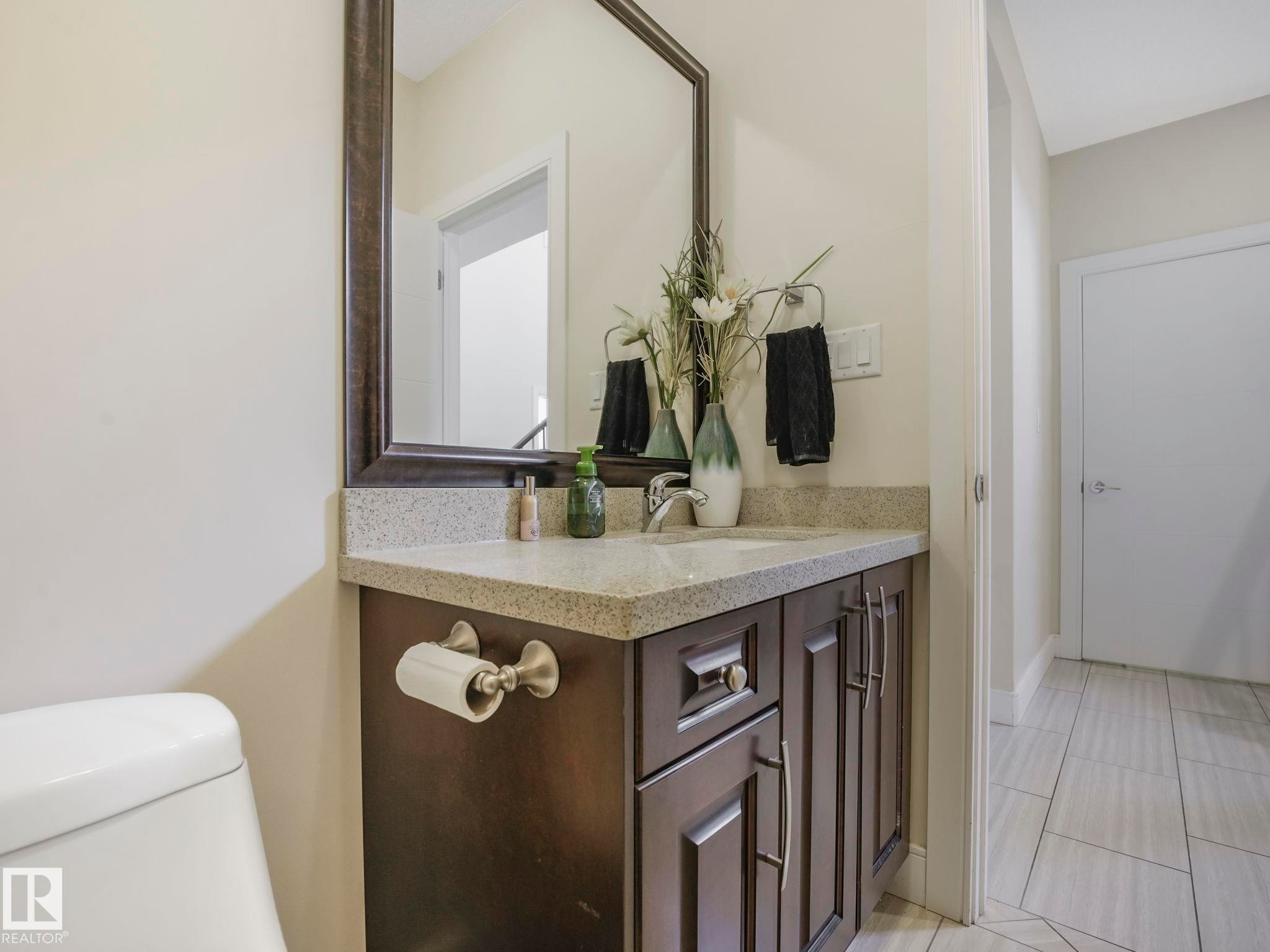 Bathroom vanity featuring a granite-style countertop, undermount sink, and dark wood cabinetry with brushed nickel hardware - 3910 49 Avenue, Beaumont, AB - Indoor Photo Showing Bathroom