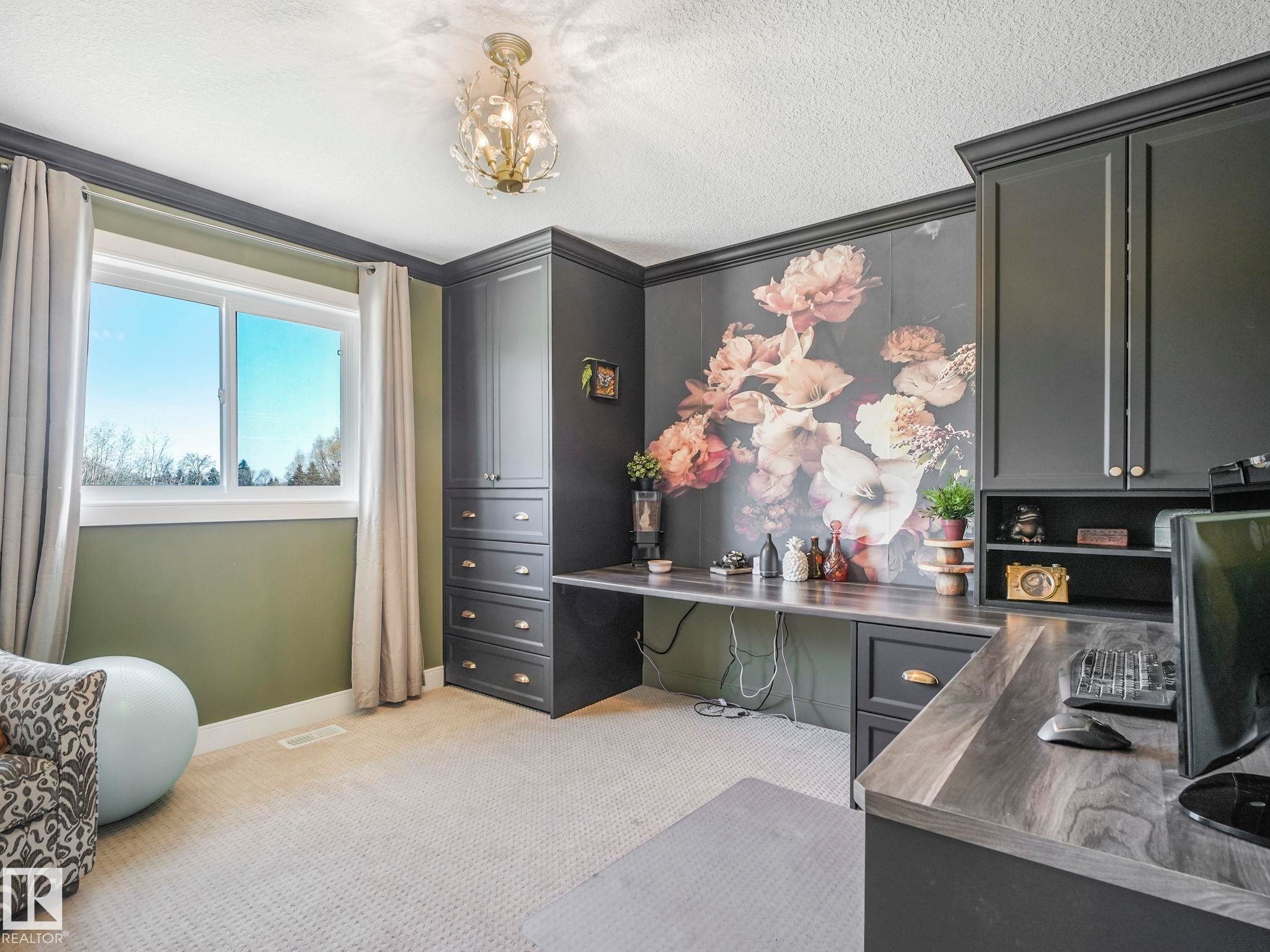 Dedicated workspace featuring extensive built-in cabinetry, wood-finish countertops, a decorative wall mural, and a contemporary chandelier - 3910 49 Avenue, Beaumont, AB - Indoor