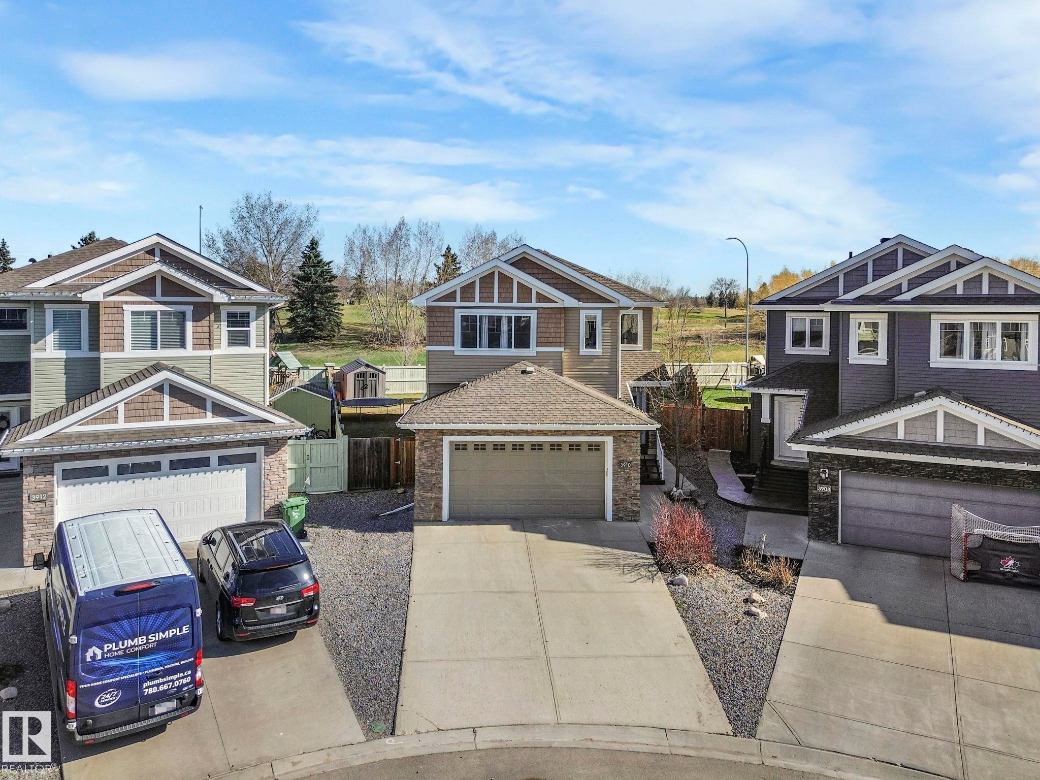 Split-level residence featuring a double-car garage, stone and shingle siding accents, and a concrete driveway - 3910 49 Avenue, Beaumont, AB - Outdoor With Facade