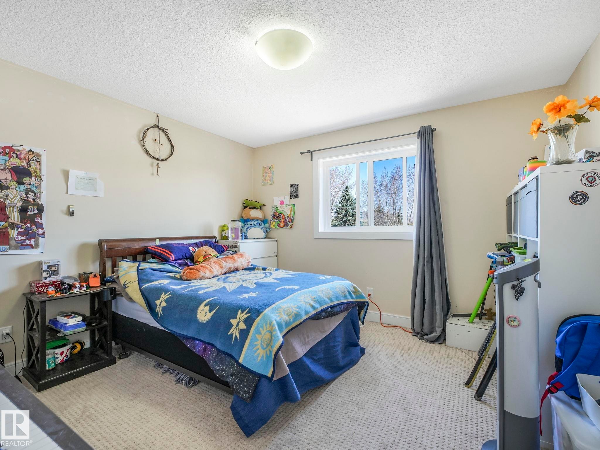 Neutral tone wall paint, textured ceiling, and light-colored carpet flooring - 3910 49 Avenue, Beaumont, AB - Indoor Photo Showing Bedroom