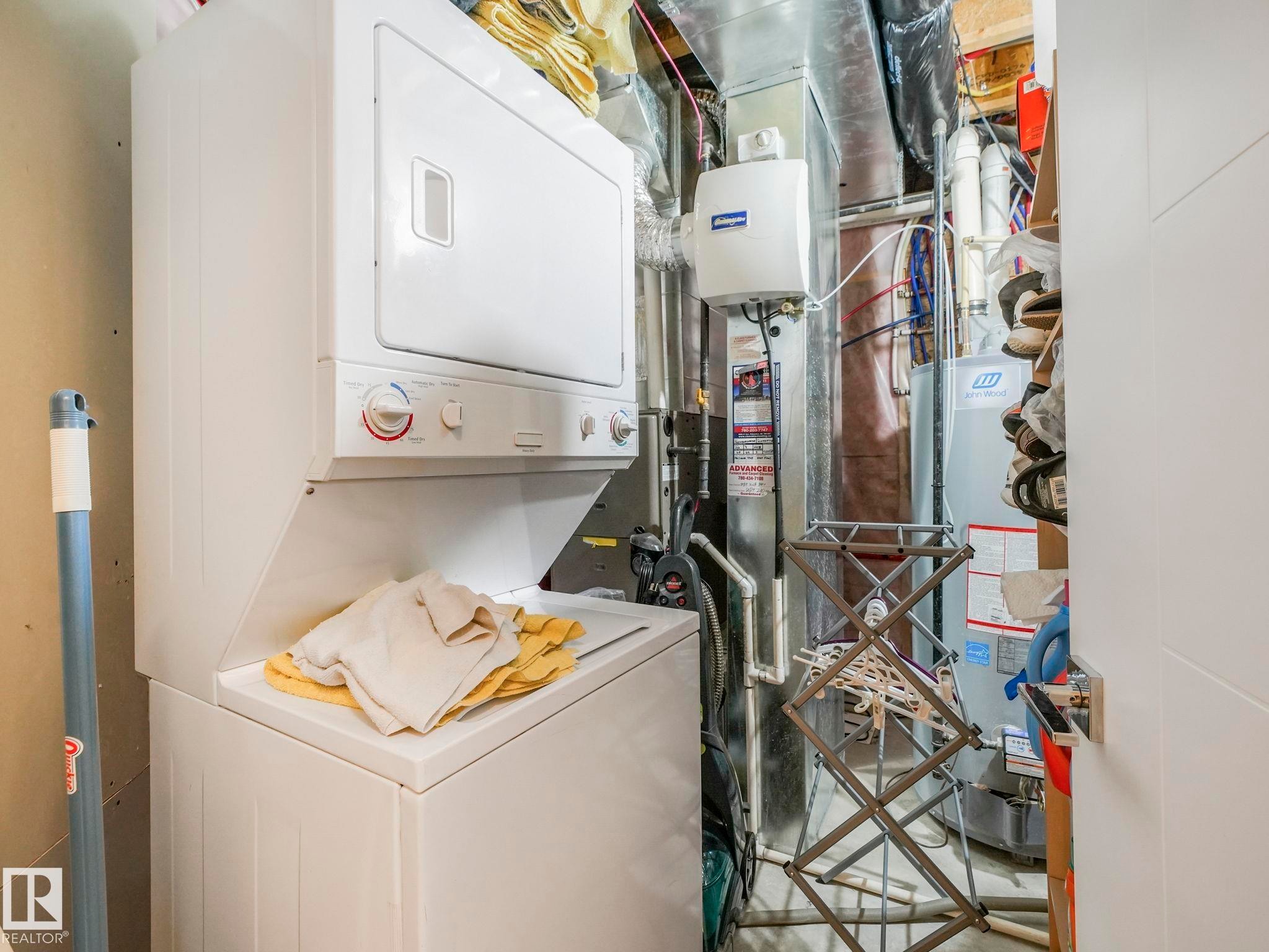 Dedicated utility area featuring a stacked washer and dryer, water heater, and furnace - 3910 49 Avenue, Beaumont, AB - Indoor Photo Showing Laundry Room