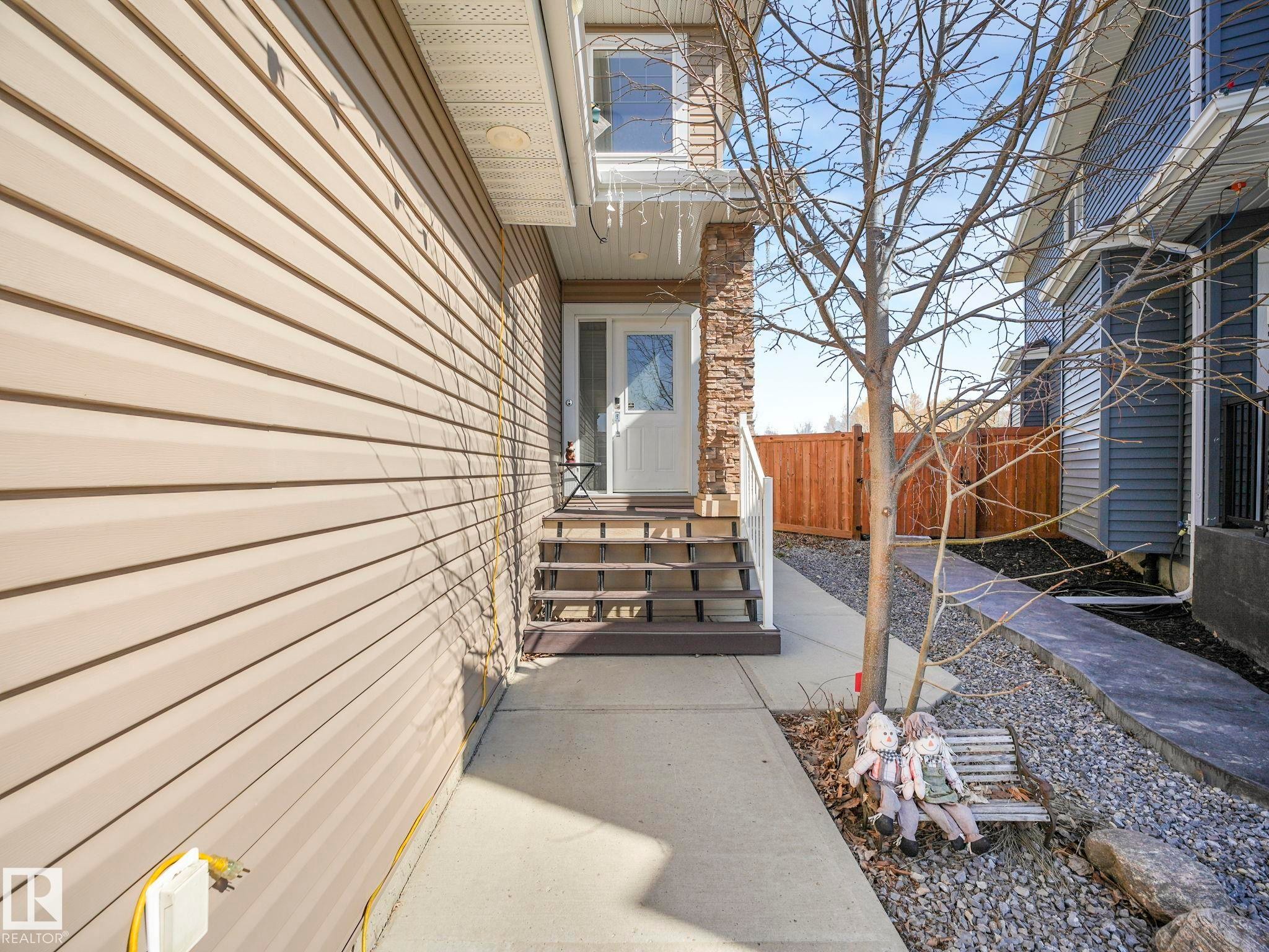 Inviting front entrance with a white door, brown steps, and a stone accent column - 3910 49 Avenue, Beaumont, AB - Outdoor