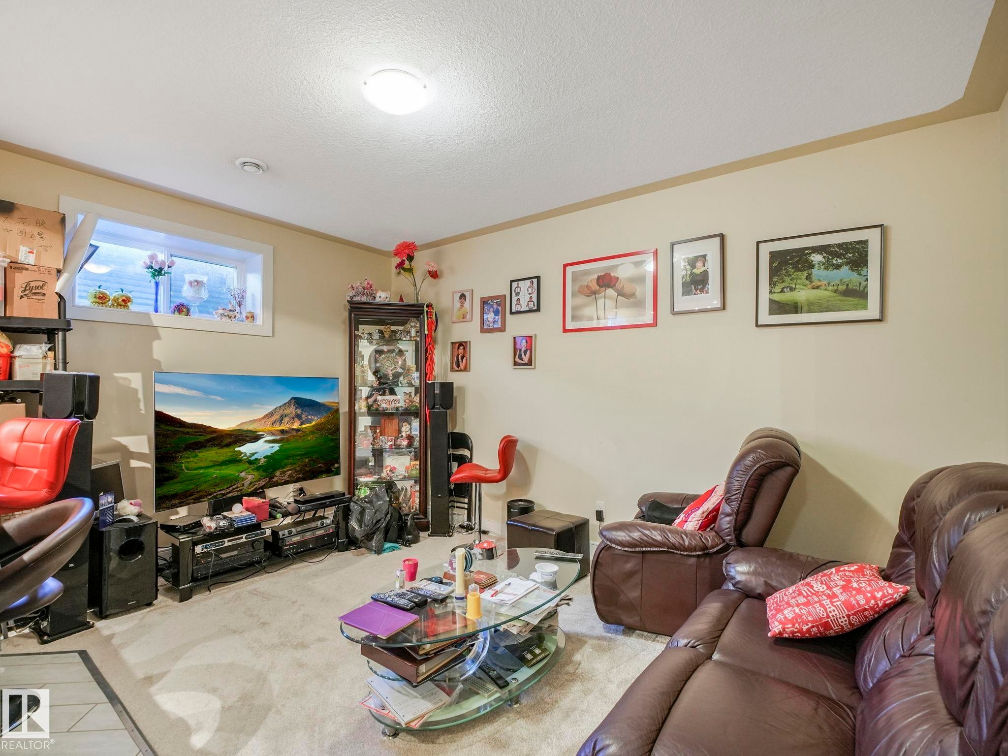 Carpeted interior space featuring a single ceiling light fixture, a window with white trim, and light beige wall paint - 3910 49 Avenue, Beaumont, AB - Indoor