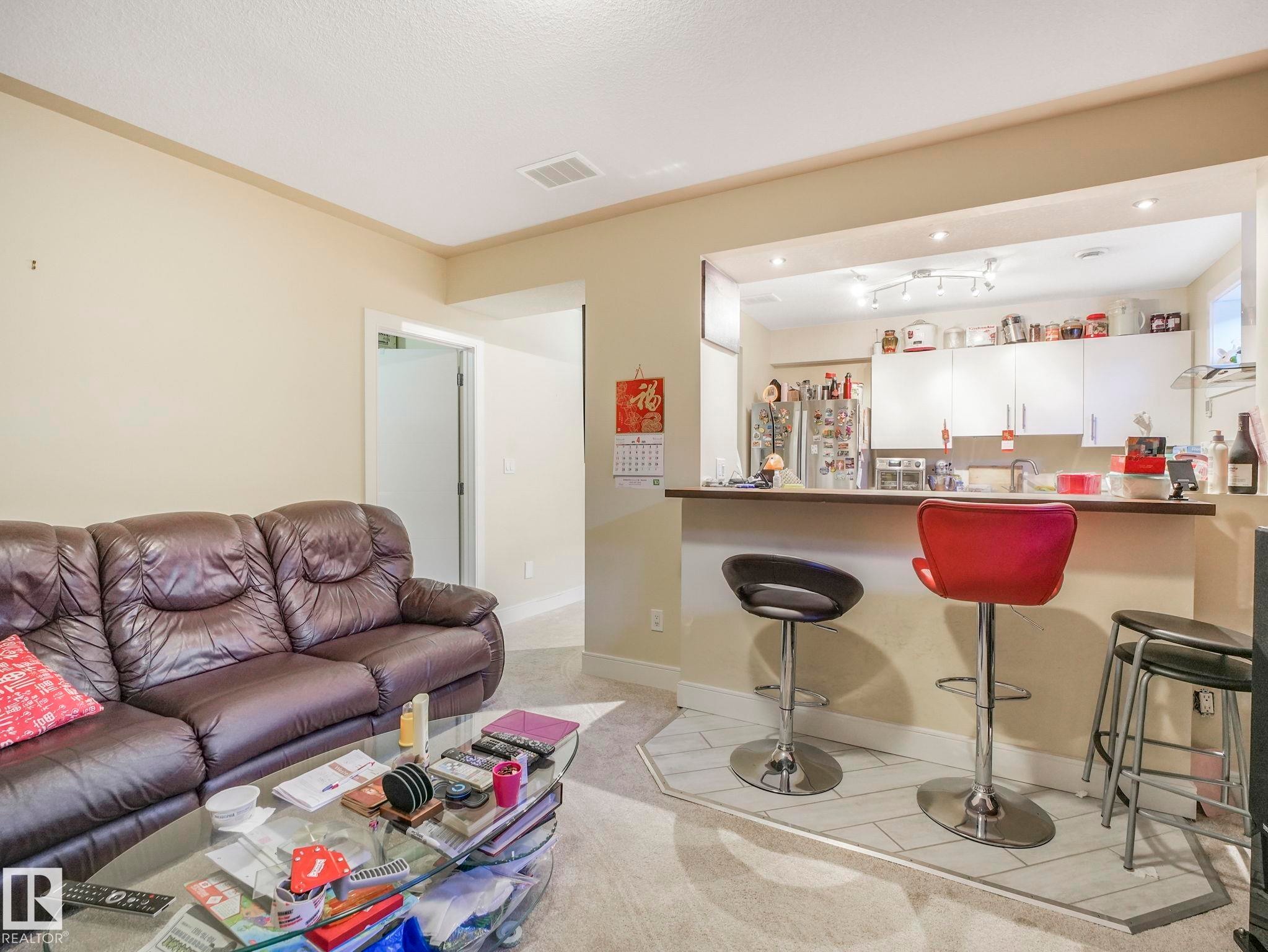 Open-concept living area featuring a kitchen pass-through with a breakfast bar, recessed lighting, and light-colored carpeting - 3910 49 Avenue, Beaumont, AB - Indoor Photo Showing Living Room