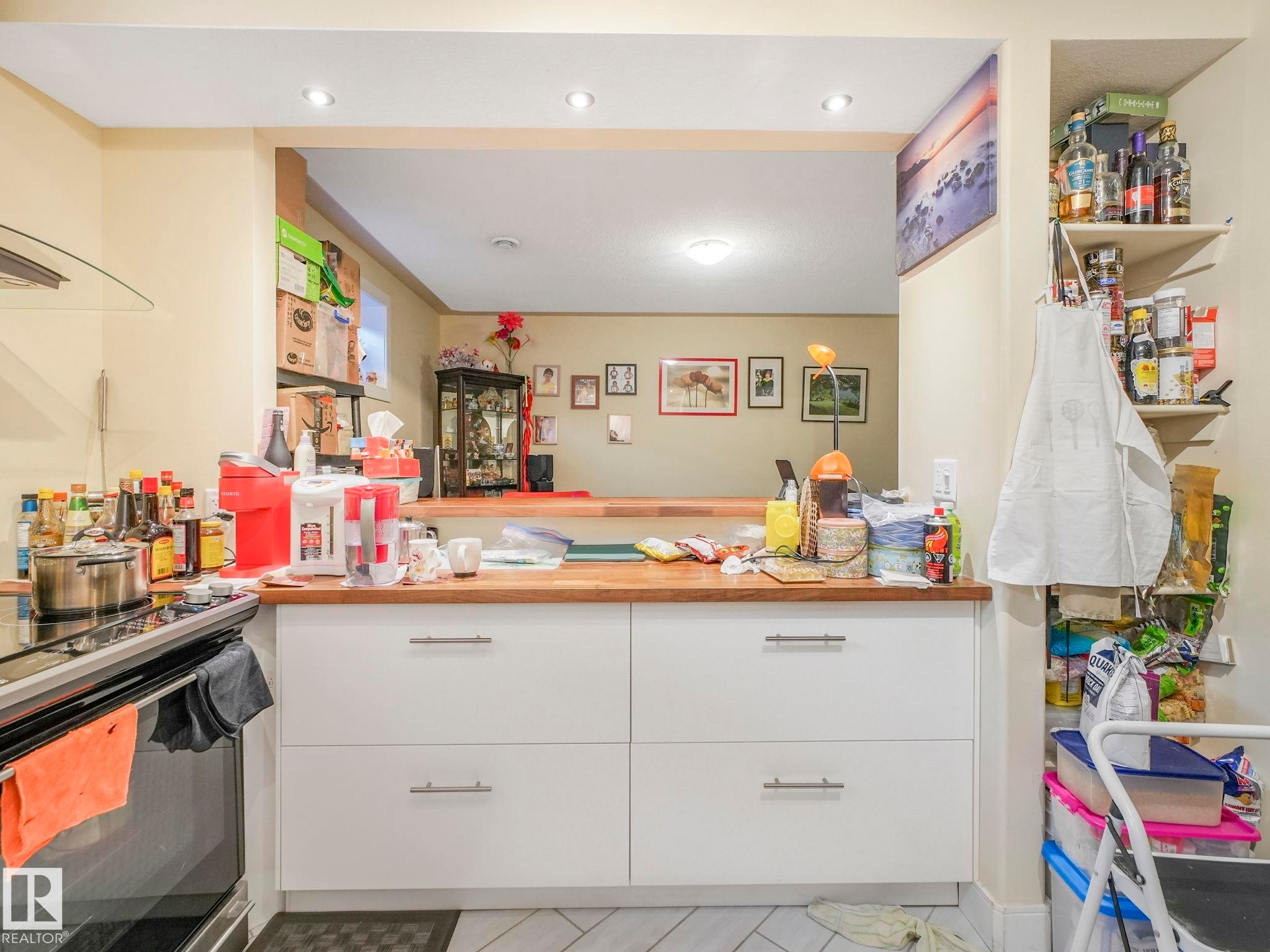 Kitchen featuring white cabinetry with silver hardware, butcher block countertops, a black electric range, and integrated open shelving - 3910 49 Avenue, Beaumont, AB - Indoor
