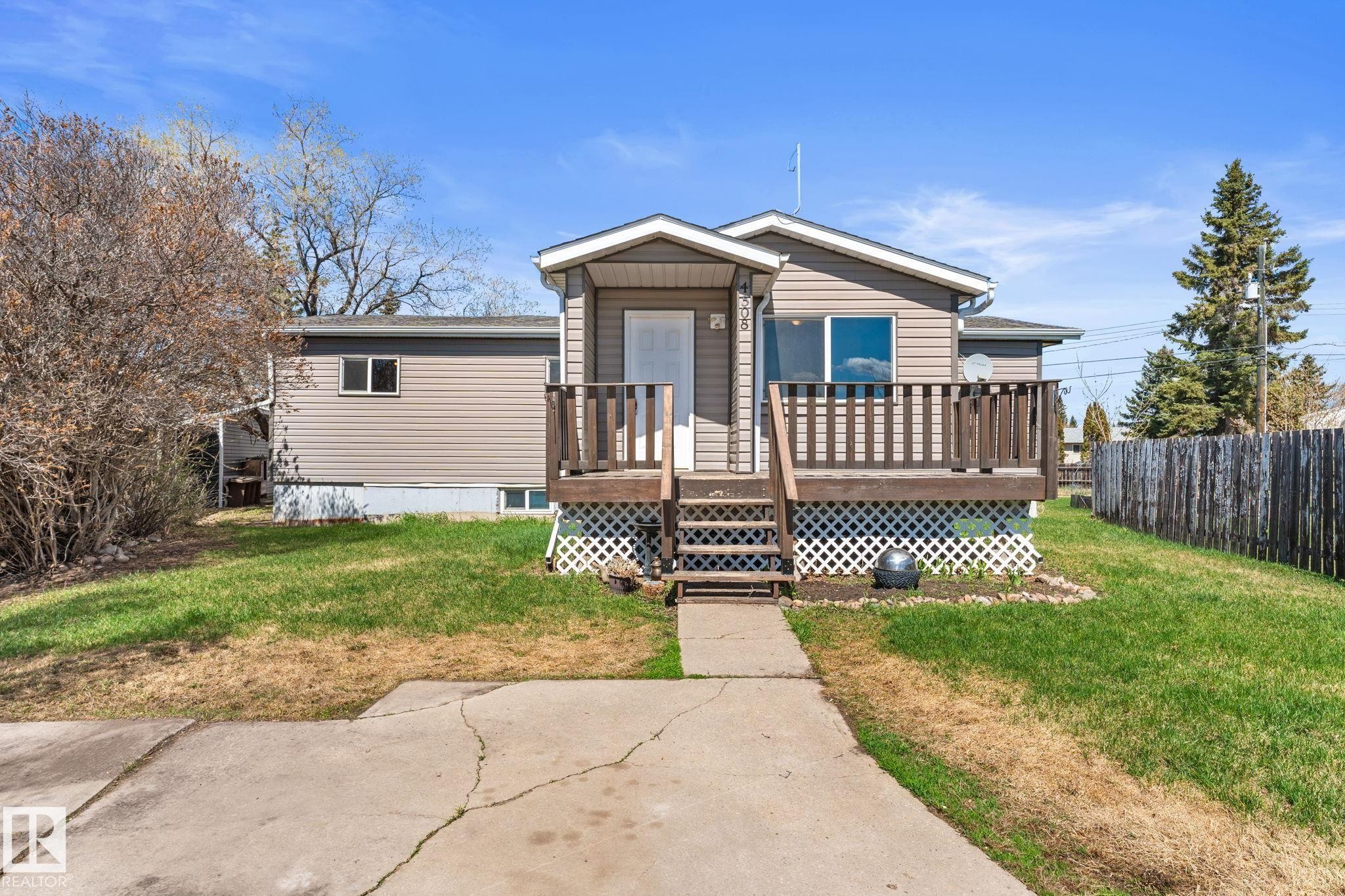 Single-story residence featuring tan siding and a covered front entry - 4508 50A Avenue, Barrhead, AB - Outdoor With Deck Patio Veranda