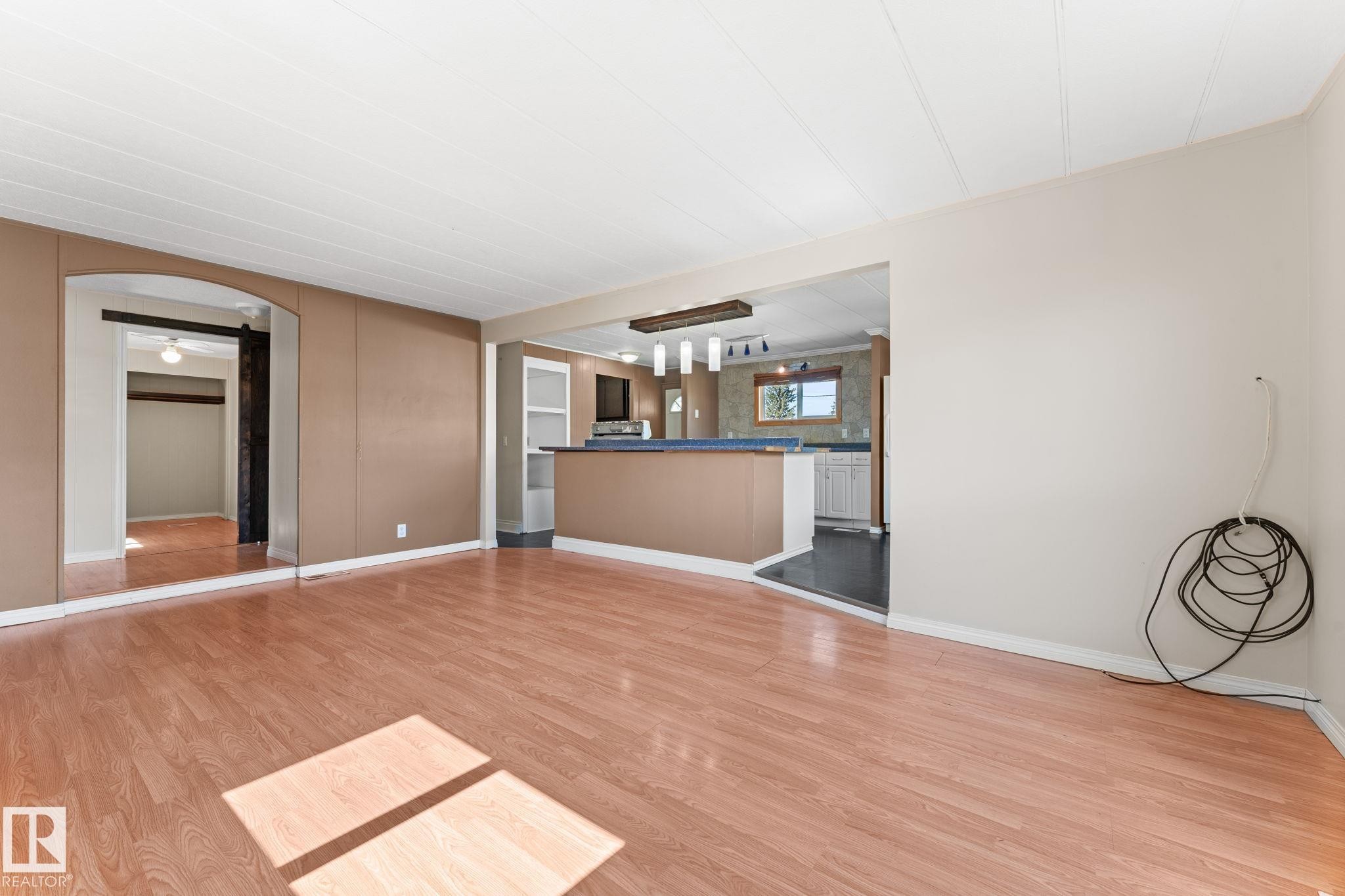 Expansive interior space featuring wood-finish flooring, an arched doorway, and a breakfast bar with built-in shelving - 4508 50A Avenue, Barrhead, AB - Indoor Photo Showing Other Room