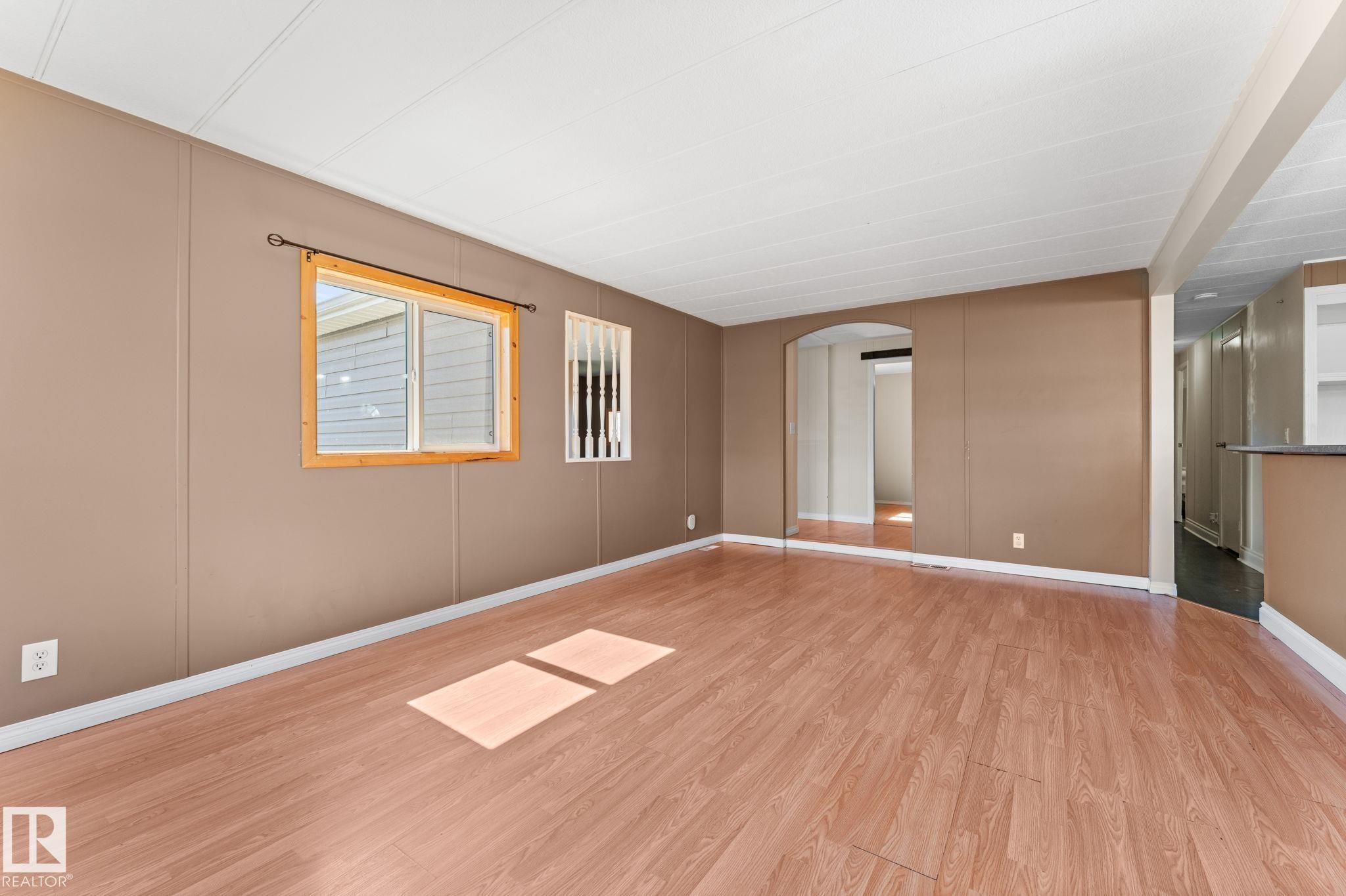 Expansive interior space featuring wood-finish flooring, a neutral wall palette, and white baseboards - 4508 50A Avenue, Barrhead, AB - Indoor Photo Showing Other Room