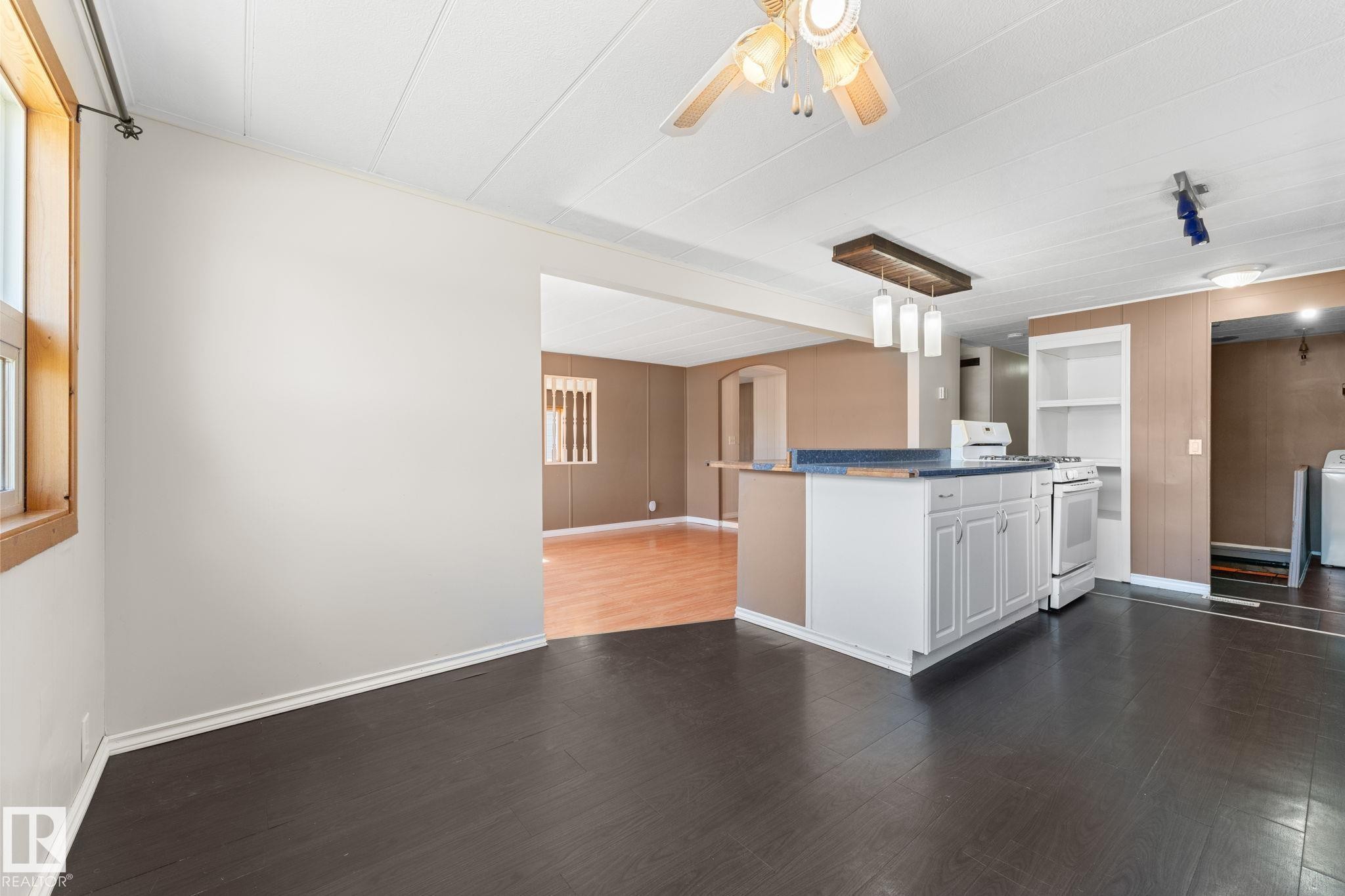 Open-concept kitchen featuring white cabinetry, a blue countertop, and integrated white appliances including a range - 4508 50A Avenue, Barrhead, AB - Indoor Photo Showing Kitchen