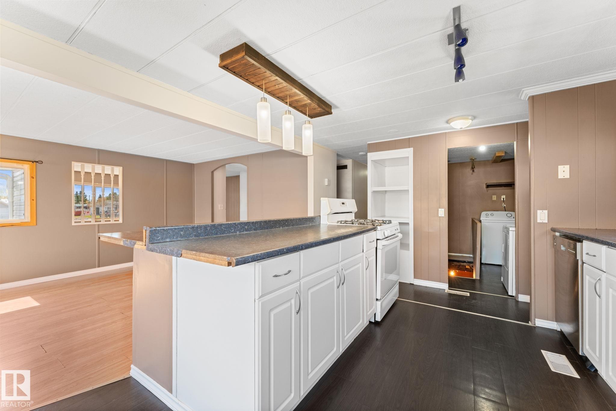 Kitchen island with white cabinetry and dark countertops - 4508 50A Avenue, Barrhead, AB - Indoor Photo Showing Kitchen
