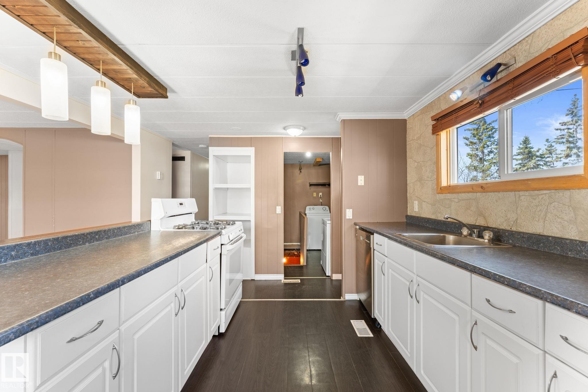 Kitchen featuring white cabinetry, dark countertops, a double basin stainless steel sink, and wood-finish flooring - 4508 50A Avenue, Barrhead, AB - Indoor Photo Showing Kitchen