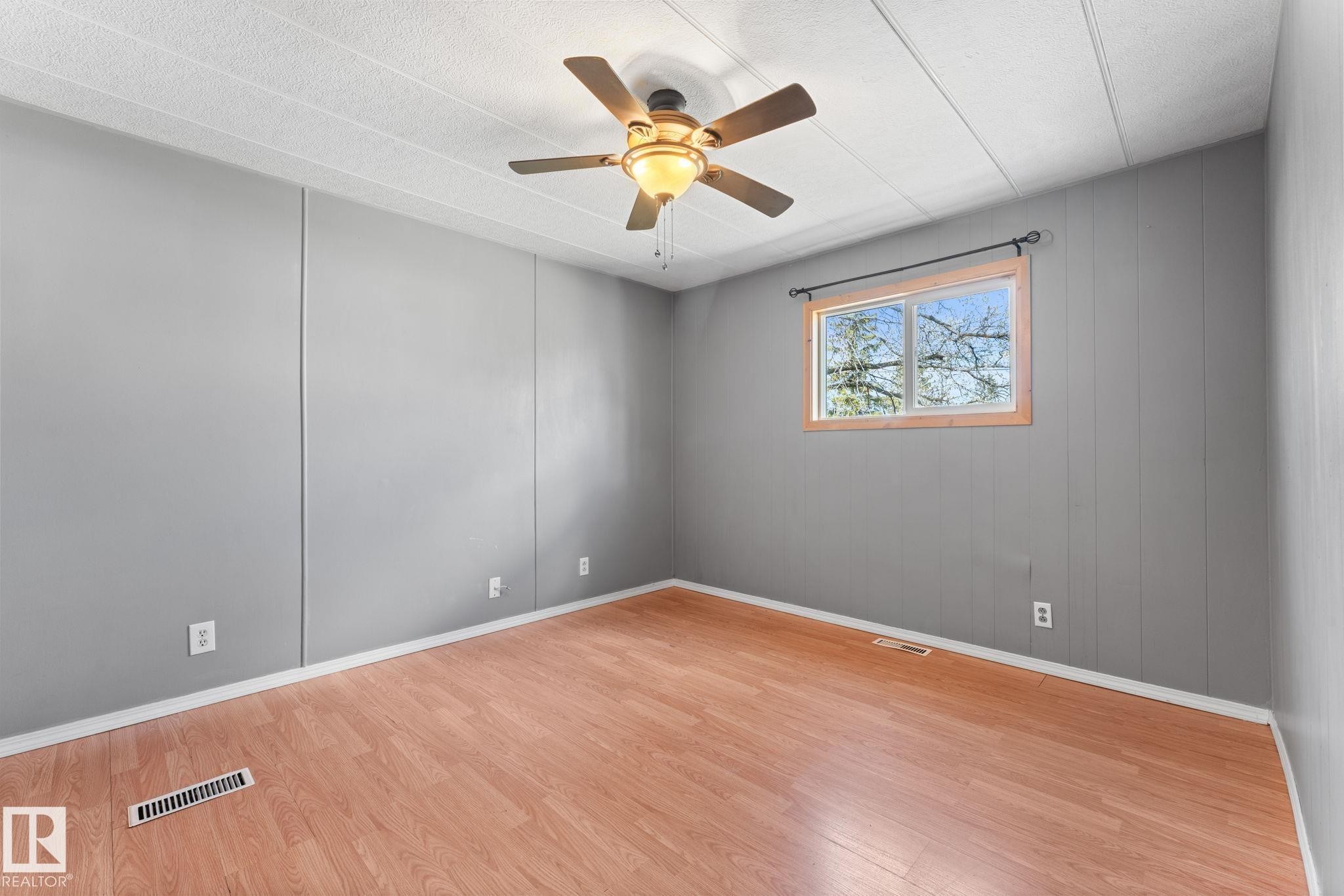 Room featuring wood-finish flooring, light gray paneled walls, and a white ceiling - 4508 50A Avenue, Barrhead, AB - Indoor Photo Showing Other Room