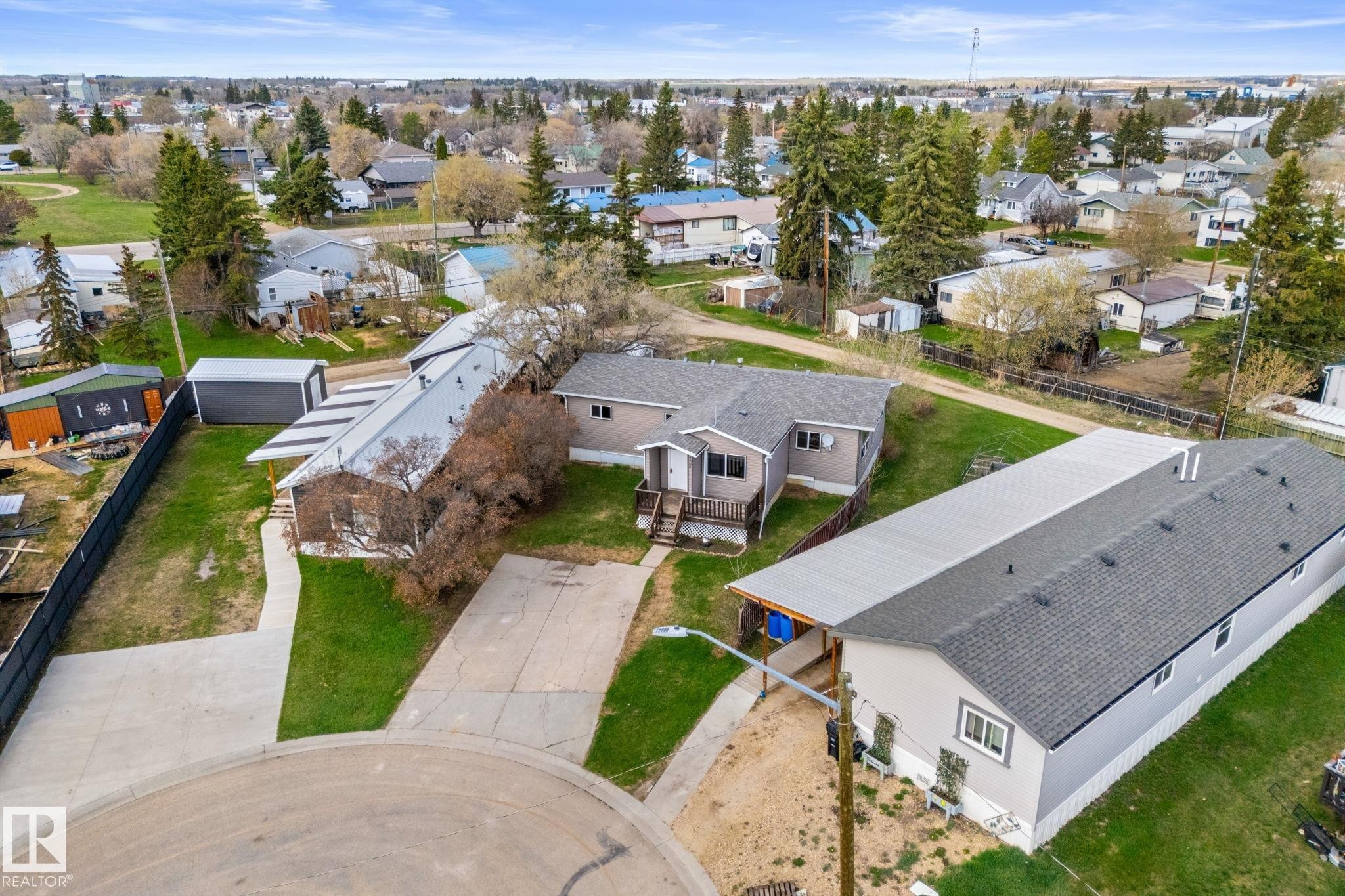 Residential property featuring a light-colored exterior, an extended covered structure, and a paved driveway - 4508 50A Avenue, Barrhead, AB - Outdoor With View