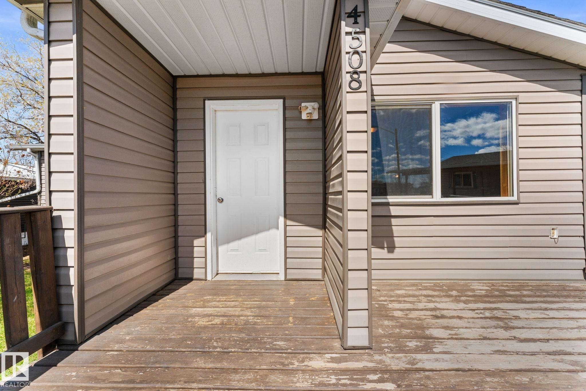Entry porch featuring horizontal siding, a white entry door, and a white-framed window - 4508 50A Avenue, Barrhead, AB - Outdoor With Exterior