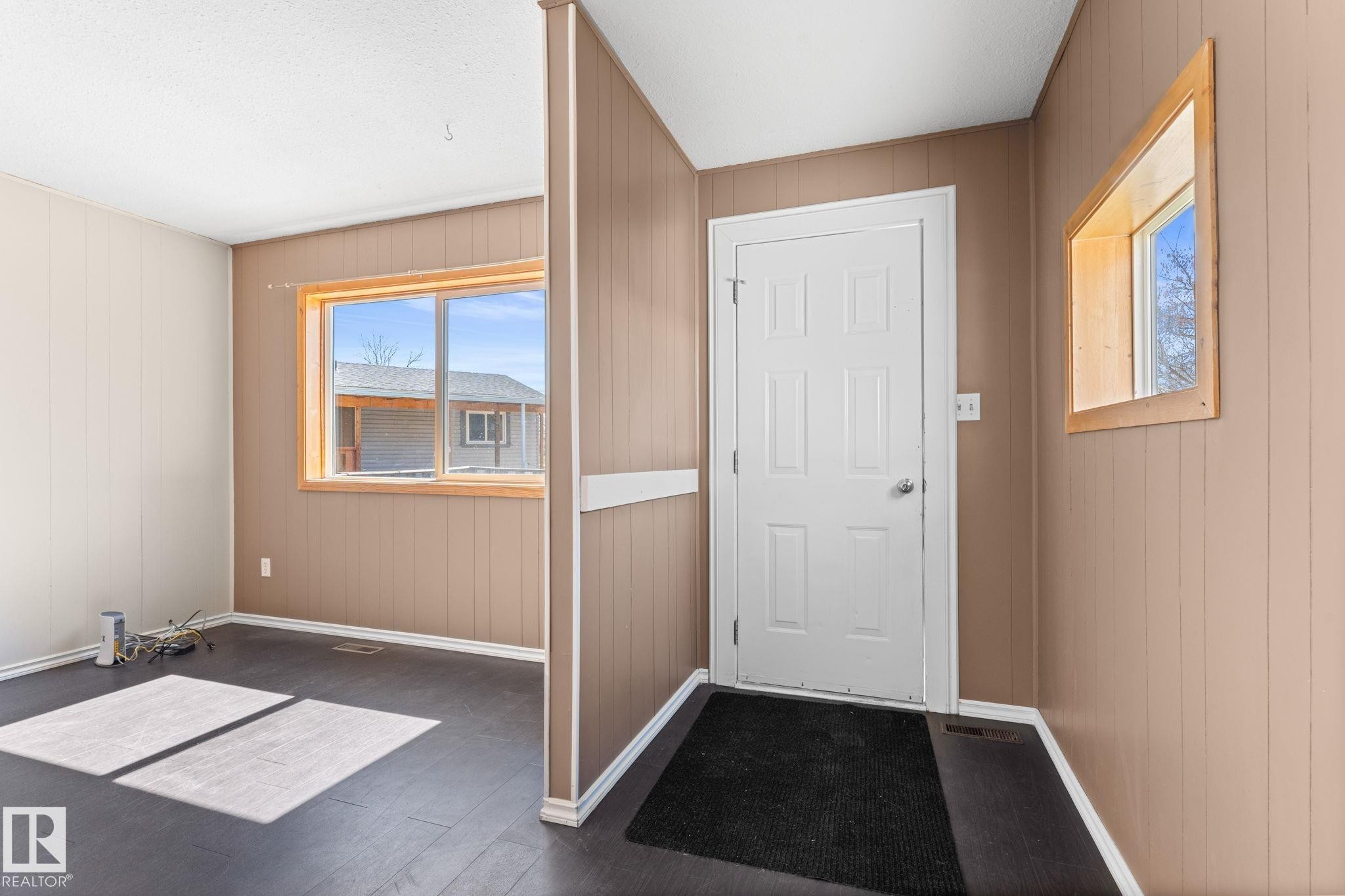 Entryway featuring a white paneled door, wood-finish flooring, and a large window with wood trim - 4508 50A Avenue, Barrhead, AB - Indoor Photo Showing Other Room
