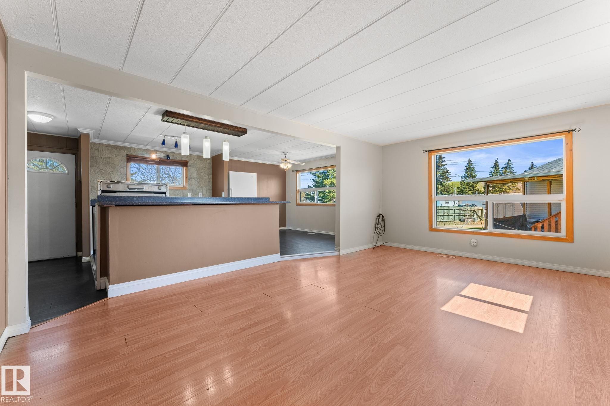 Open-concept living area featuring wood-finish flooring and a large picture window - 4508 50A Avenue, Barrhead, AB - Indoor Photo Showing Other Room