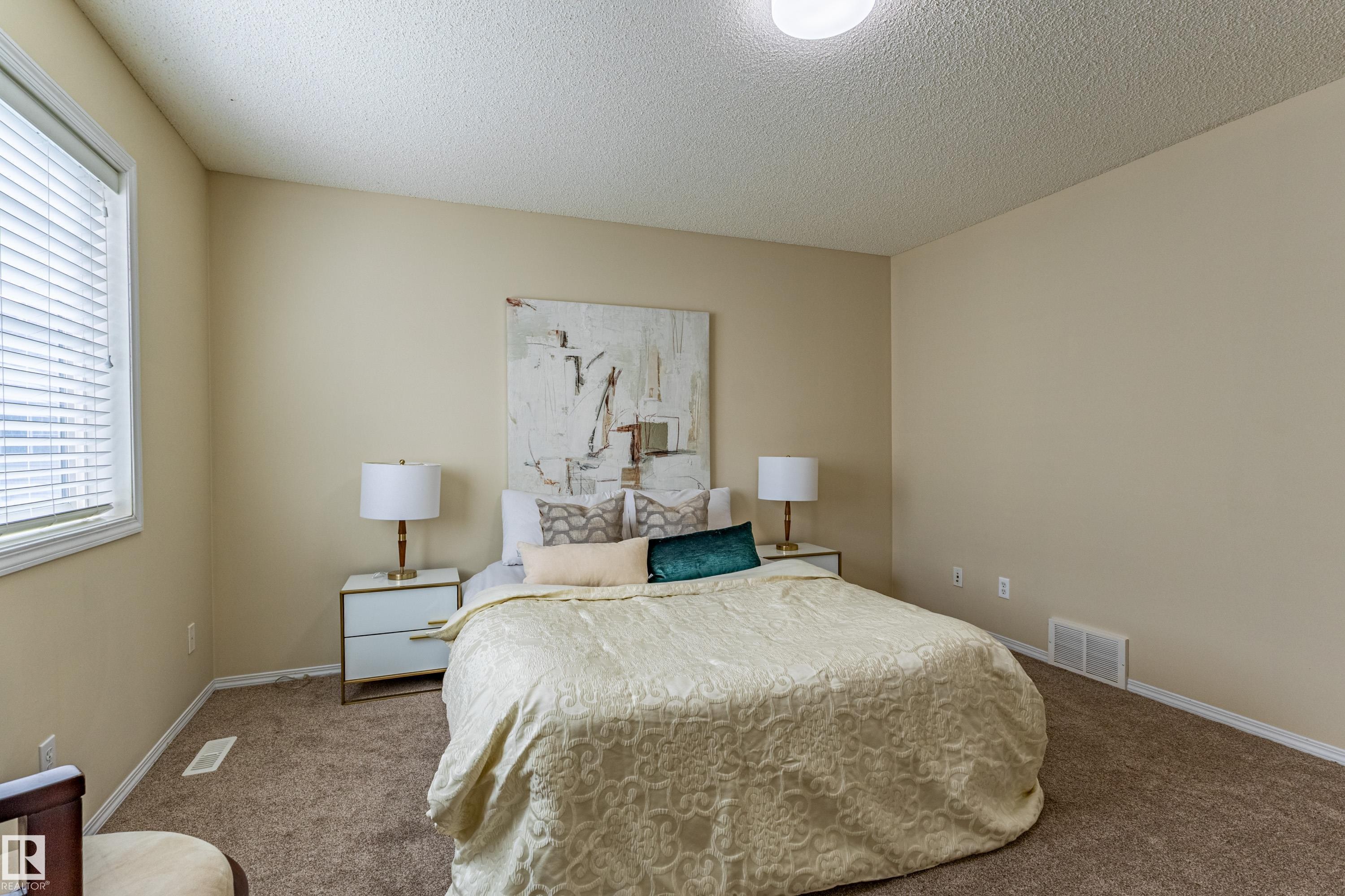 Bedroom featuring neutral-toned walls, textured carpeting, and a window with horizontal blinds - 41 8304 11 Avenue, Edmonton, AB - Indoor Photo Showing Bedroom