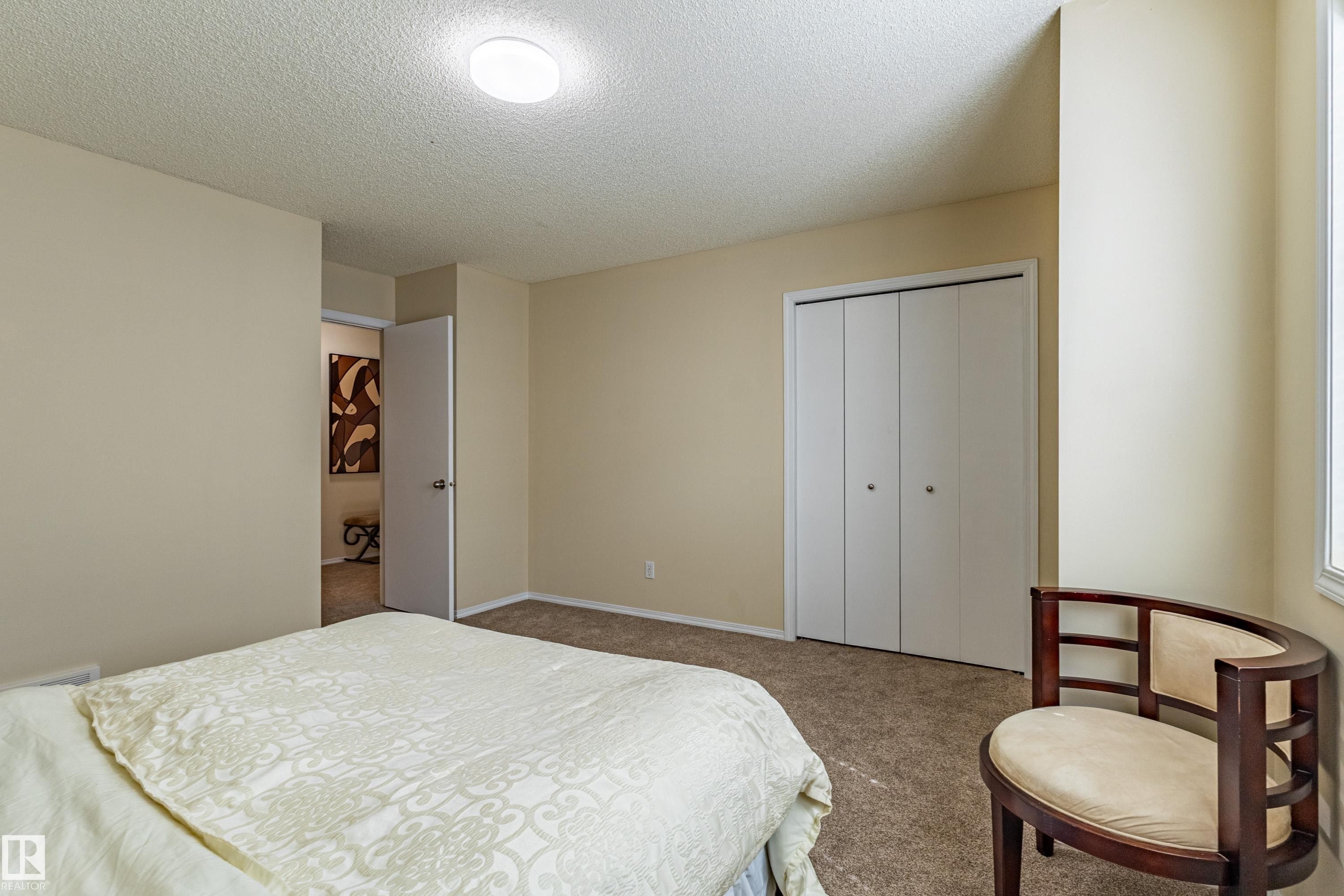 Carpeted room with neutral-toned walls, a flush-mount ceiling light, and a white bi-fold closet - 41 8304 11 Avenue, Edmonton, AB - Indoor Photo Showing Bedroom