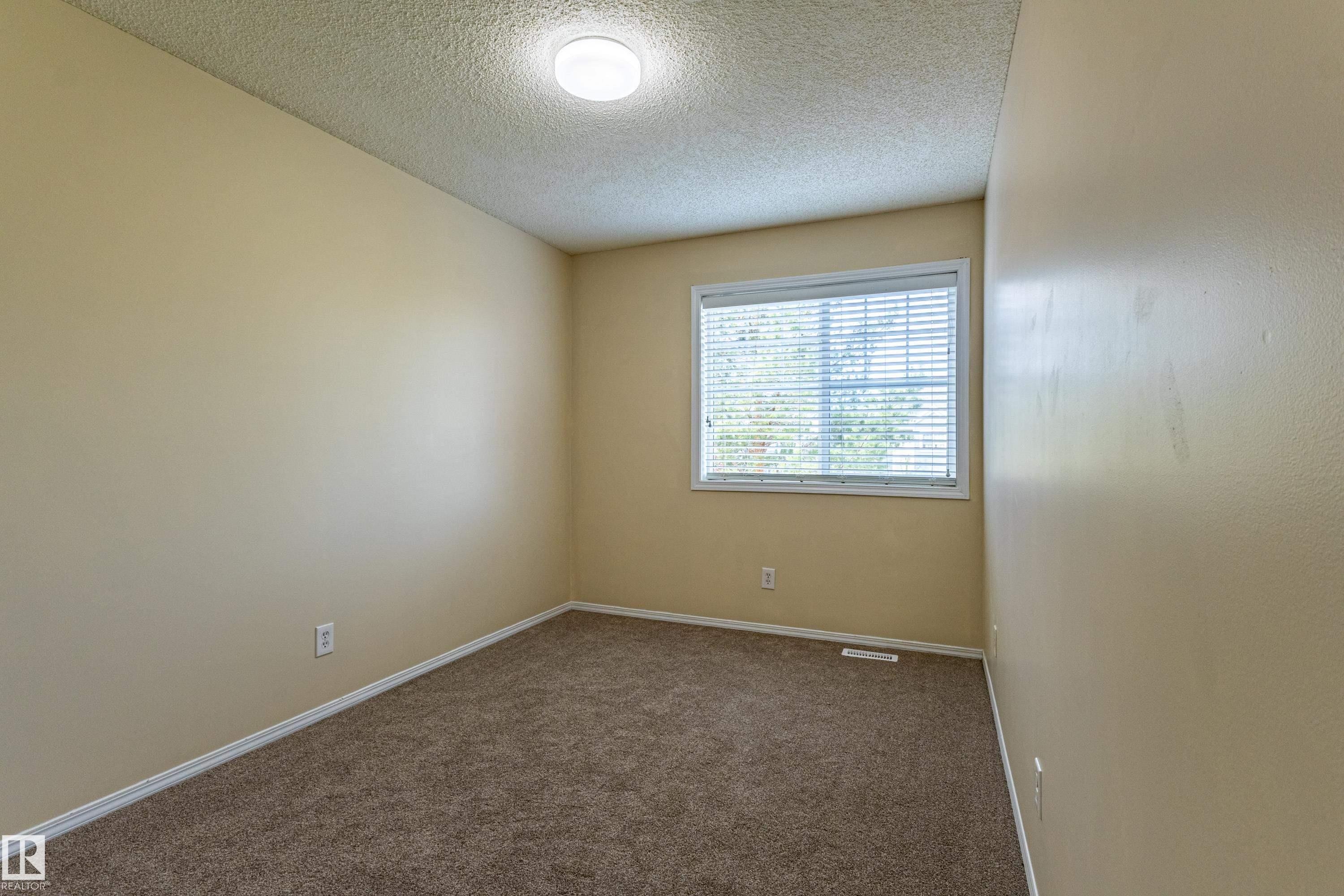 Spacious room featuring neutral-toned walls, plush carpet flooring, a single window with blinds, and a ceiling-mounted light fixture - 41 8304 11 Avenue, Edmonton, AB - Indoor Photo Showing Other Room