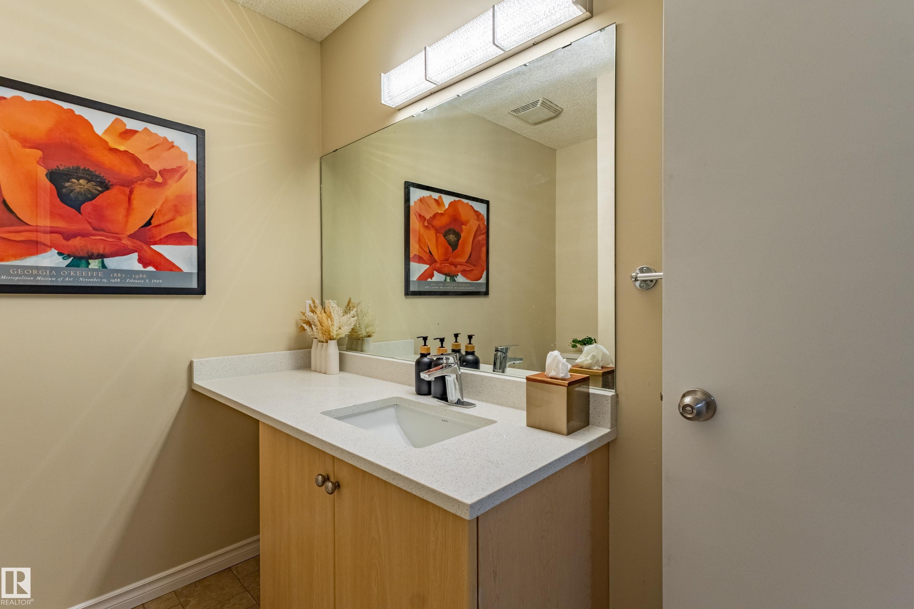 Bathroom vanity featuring an integrated sink, light-toned wood cabinetry, and a spacious countertop - 41 8304 11 Avenue, Edmonton, AB - Indoor Photo Showing Bathroom