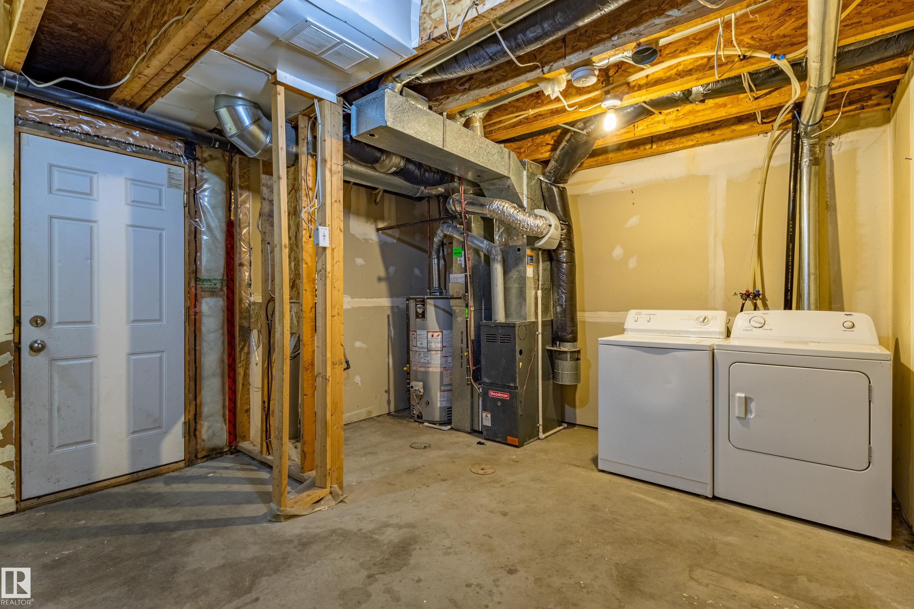 Unfinished basement space featuring exposed wood joists and concrete flooring - 41 8304 11 Avenue, Edmonton, AB - Indoor Photo Showing Laundry Room