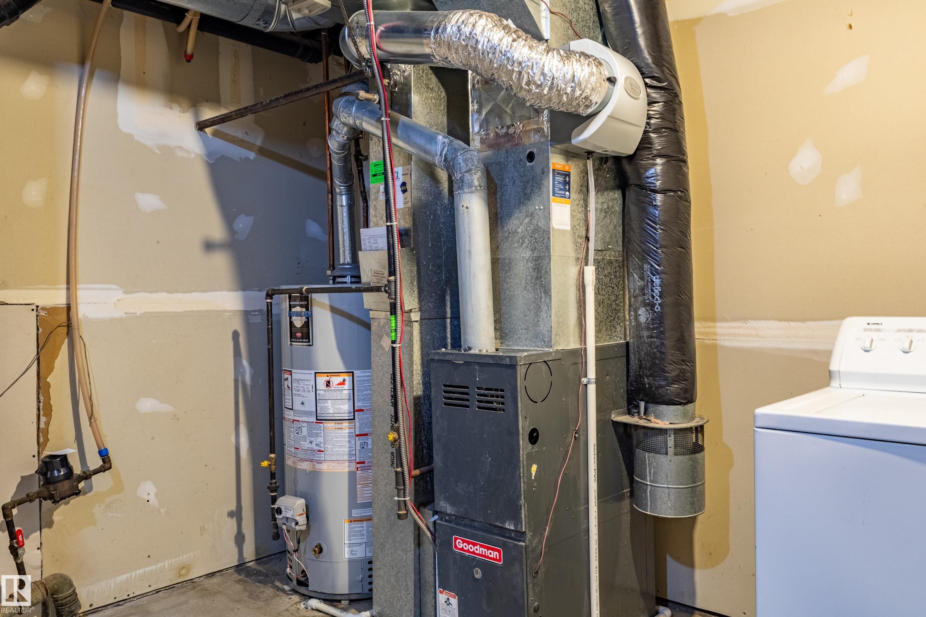 Mechanical room featuring a water heater, furnace, and exposed ductwork - 41 8304 11 Avenue, Edmonton, AB - Indoor Photo Showing Basement