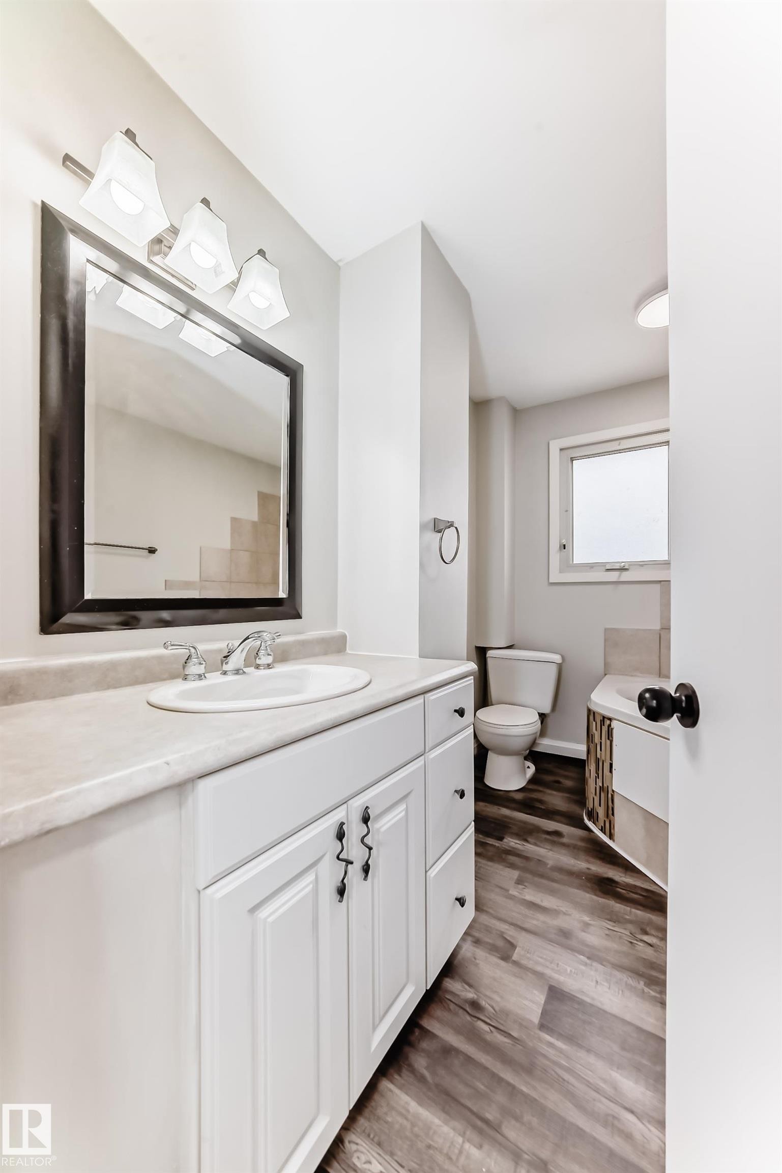 White vanity with a neutral countertop, undermount sink, and chrome faucet - 8615 42A Avenue, Edmonton, AB - Indoor Photo Showing Bathroom