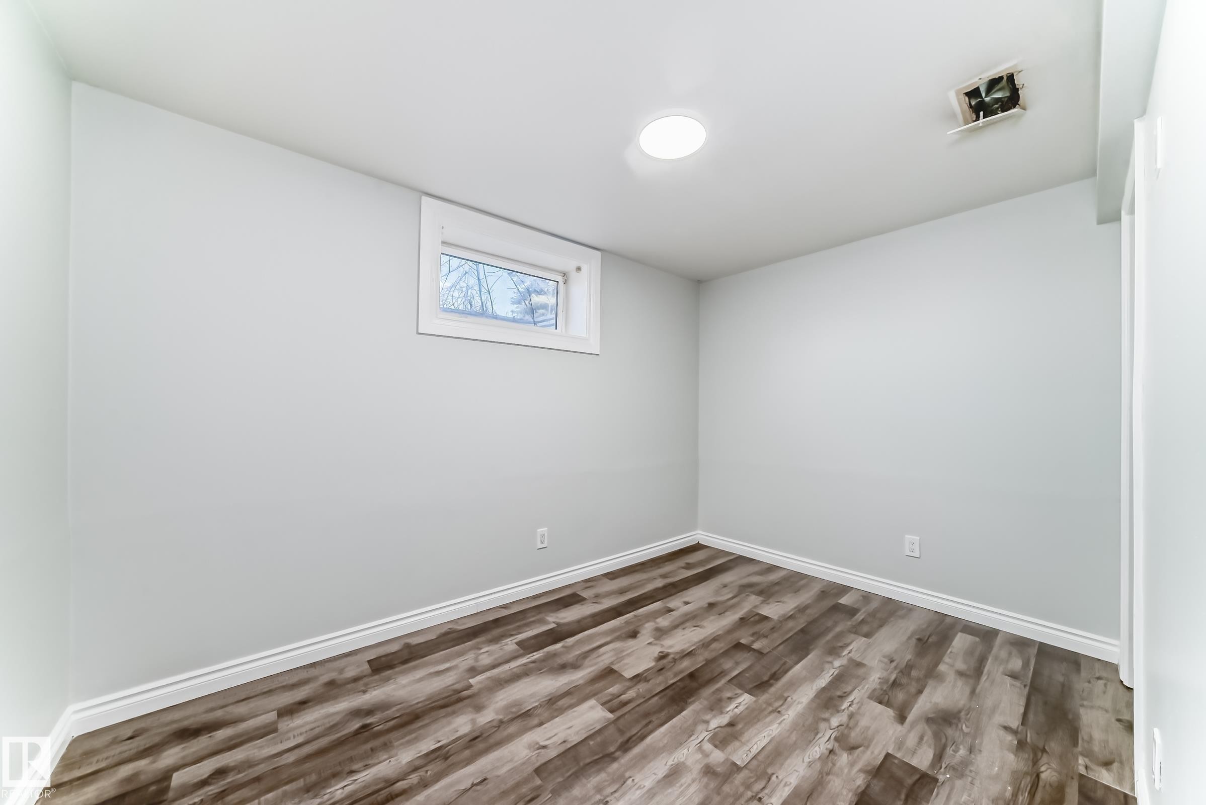 Spacious room featuring wood-finish flooring, white baseboards, and light-toned walls - 8615 42A Avenue, Edmonton, AB - Indoor Photo Showing Other Room