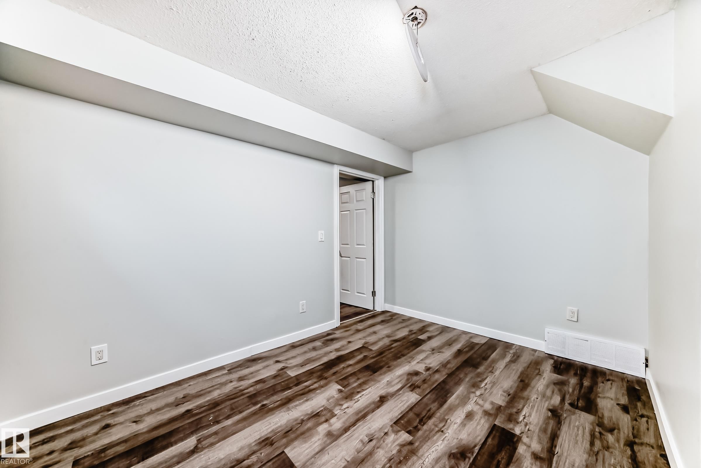 Wood-finish flooring throughout this room with light-toned walls and white baseboards - 8615 42A Avenue, Edmonton, AB - Indoor Photo Showing Other Room