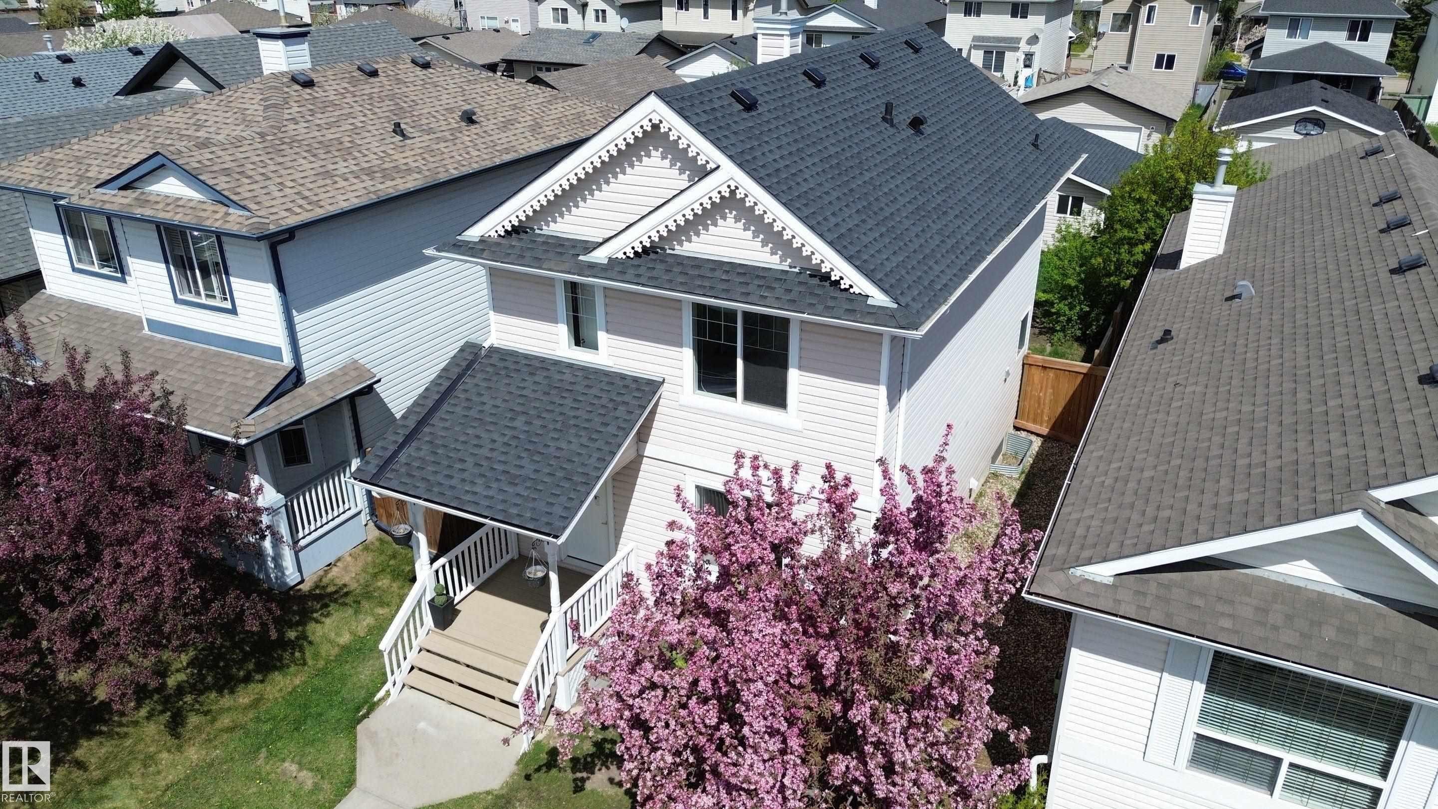 Two-story residence featuring light-colored siding, a covered front entry with white railings, and a dark asphalt shingle roof - 21344 88 Avenue, Edmonton, AB - Outdoor