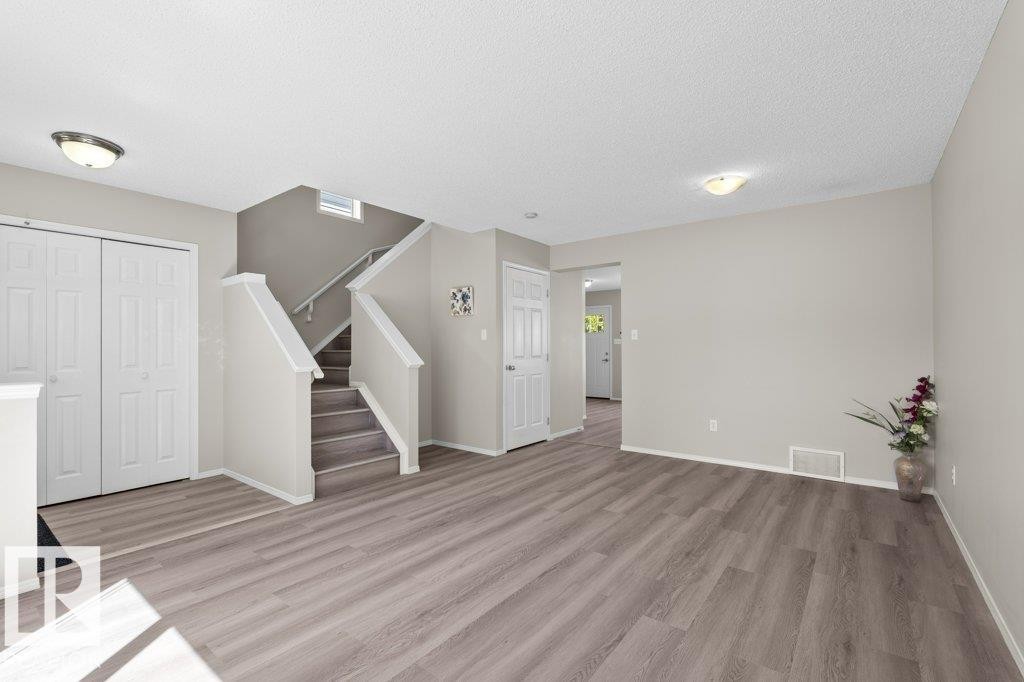 Spacious interior featuring wood-finish flooring, neutral wall tones, and a staircase with light carpeted treads - 21344 88 Avenue, Edmonton, AB - Indoor Photo Showing Other Room