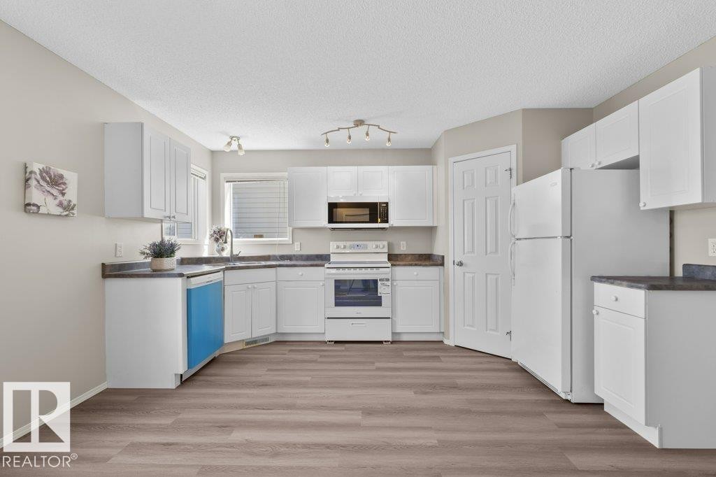 U-shaped kitchen featuring white cabinetry, dark countertops, and wood-finish flooring - 21344 88 Avenue, Edmonton, AB - Indoor Photo Showing Kitchen