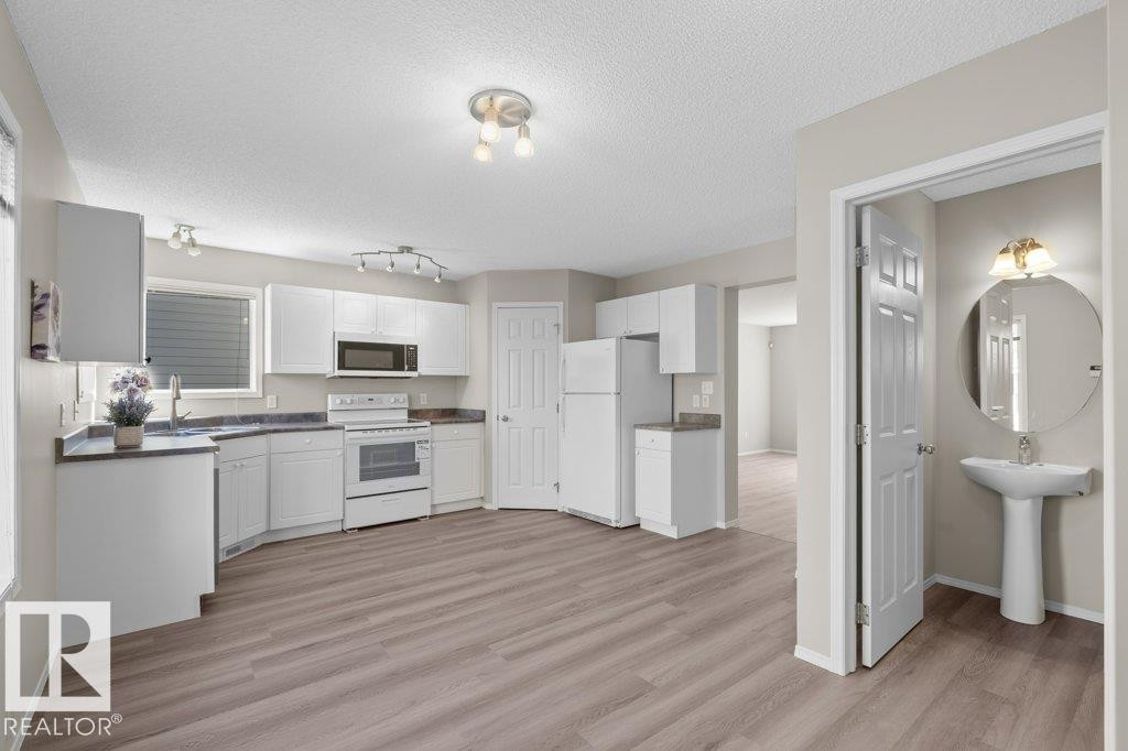 Kitchen featuring white cabinetry, white appliances, dark countertops, and wood-finish flooring - 21344 88 Avenue, Edmonton, AB - Indoor Photo Showing Kitchen