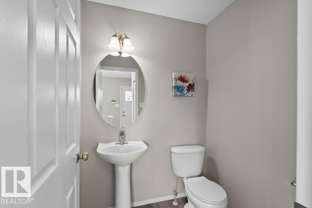 Pedestal sink with an oval mirror and two-light vanity fixture - 21344 88 Avenue, Edmonton, AB - Indoor Photo Showing Bathroom