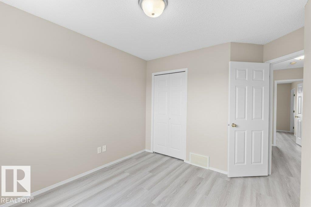 Light wood-finish flooring complements the neutral wall color and white trim - 21344 88 Avenue, Edmonton, AB - Indoor Photo Showing Other Room