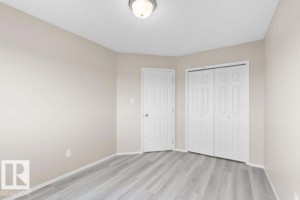 Room featuring wood-finish flooring, neutral wall paint, white trim, and a ceiling-mounted light fixture - 21344 88 Avenue, Edmonton, AB - Indoor