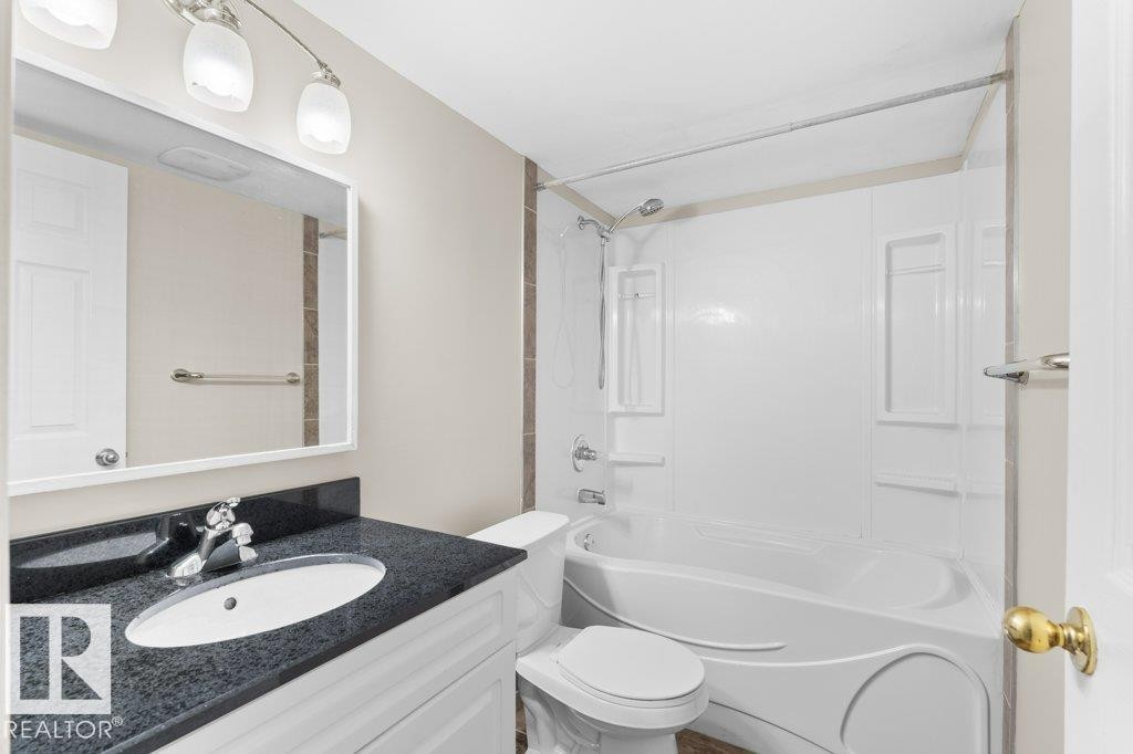Full bathroom featuring a white vanity with dark speckled countertop, undermount sink, and polished chrome faucet - 21344 88 Avenue, Edmonton, AB - Indoor Photo Showing Bathroom