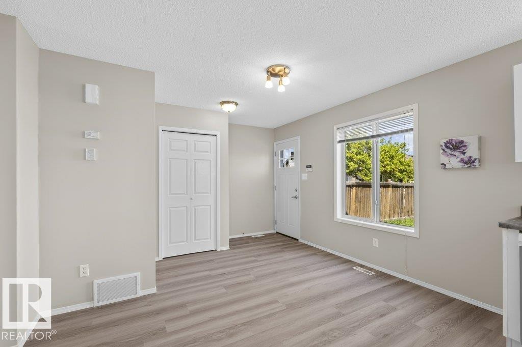 Entryway featuring wood-finish flooring, a white front door with decorative glass, and a large window overlooking a wooden privacy fence - 21344 88 Avenue, Edmonton, AB - Indoor Photo Showing Other Room