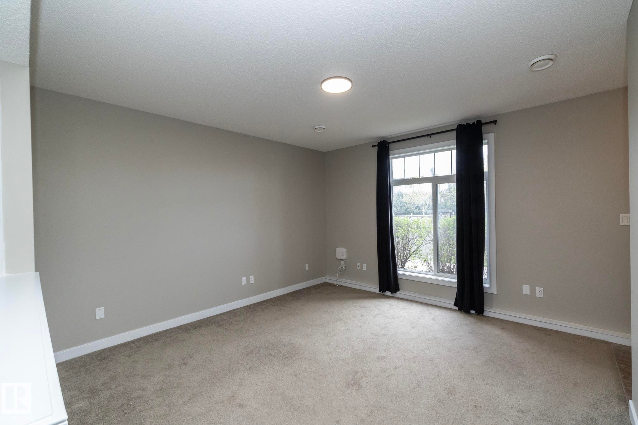 Carpeted room featuring neutral wall paint, white baseboards, and a large window with white trim - 117 Callaghan Drive Sw, Edmonton, AB - Indoor Photo Showing Other Room