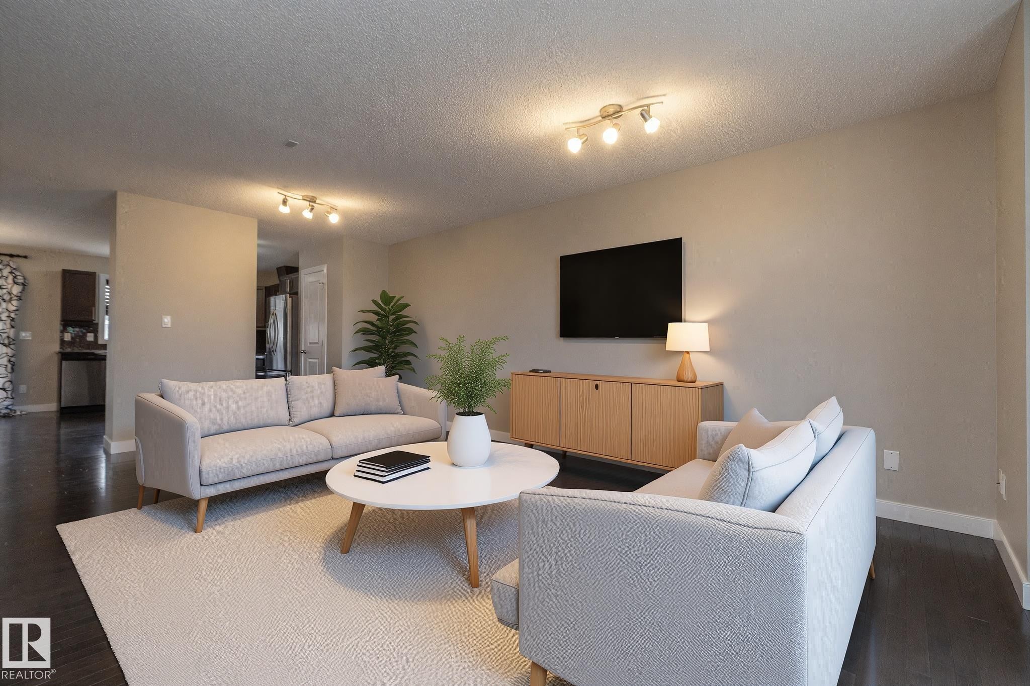 Spacious living area featuring dark wood-finish flooring, light neutral wall tones, and recessed track lighting fixtures - 117 Callaghan Drive Sw, Edmonton, AB - Indoor Photo Showing Living Room