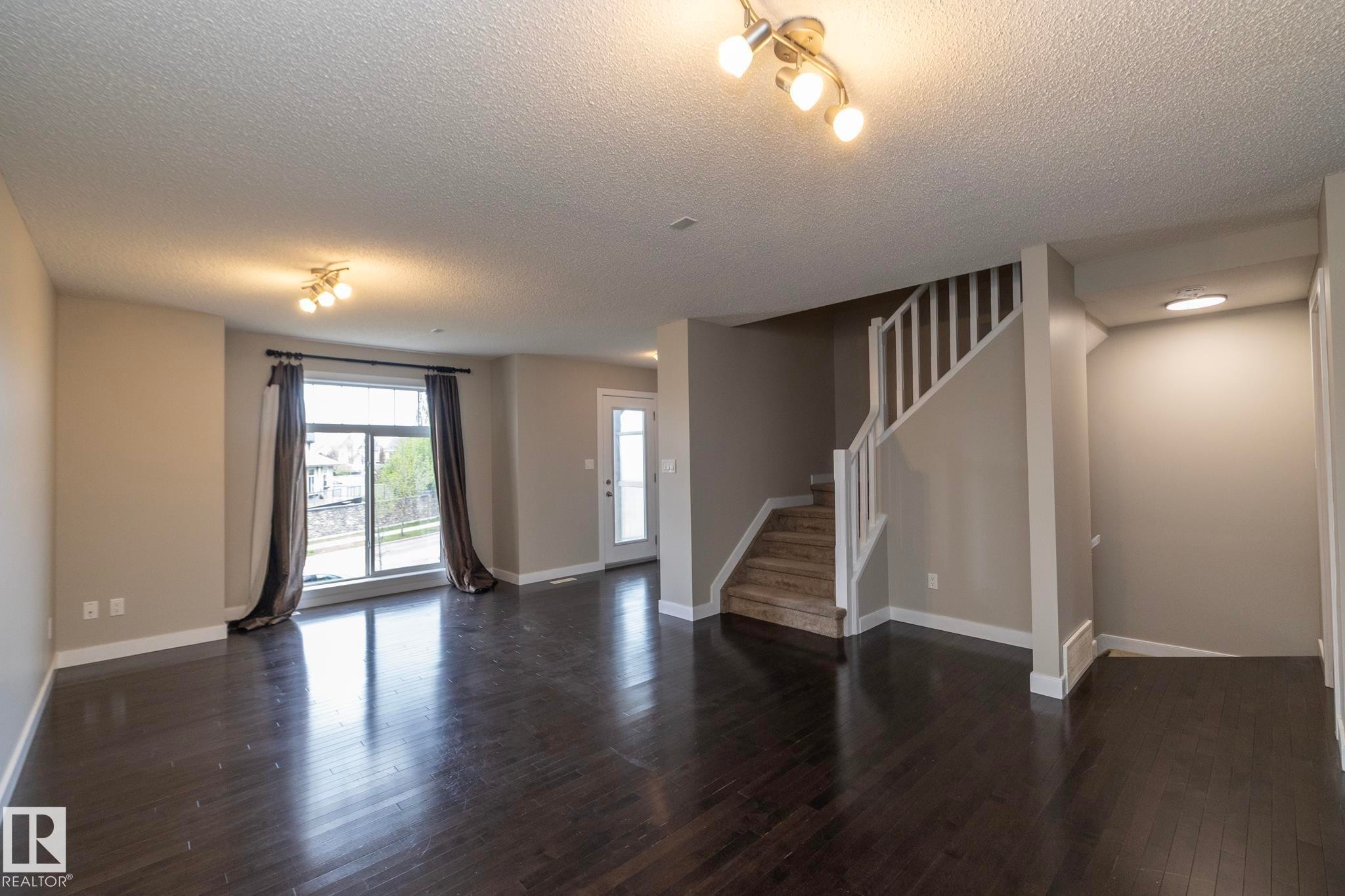 Dark wood-finish flooring complements light-toned walls in this interior space - 117 Callaghan Drive Sw, Edmonton, AB - Indoor