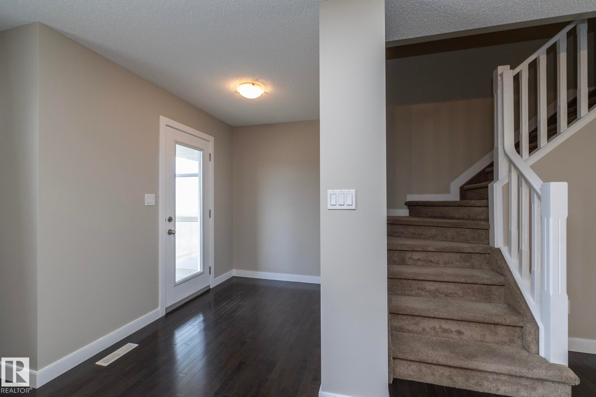 Entryway featuring dark wood-finish flooring, light grey painted walls, white trim, and a glass-paneled door - 117 Callaghan Drive Sw, Edmonton, AB - Indoor Photo Showing Other Room