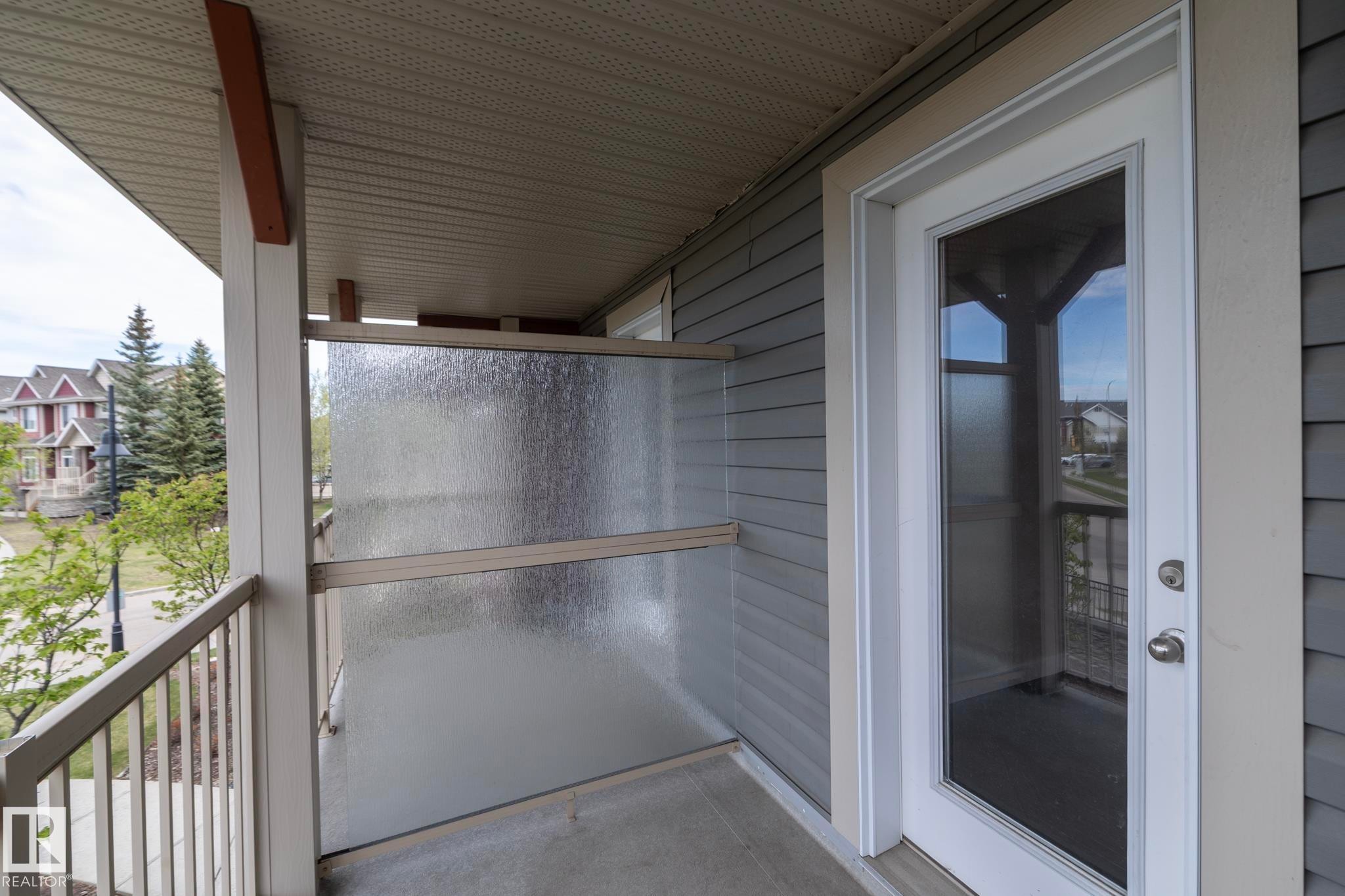 Private balcony featuring a full-light exterior door, textured privacy paneling, painted metal railings, and vinyl siding - 117 Callaghan Drive Sw, Edmonton, AB - Outdoor With Exterior