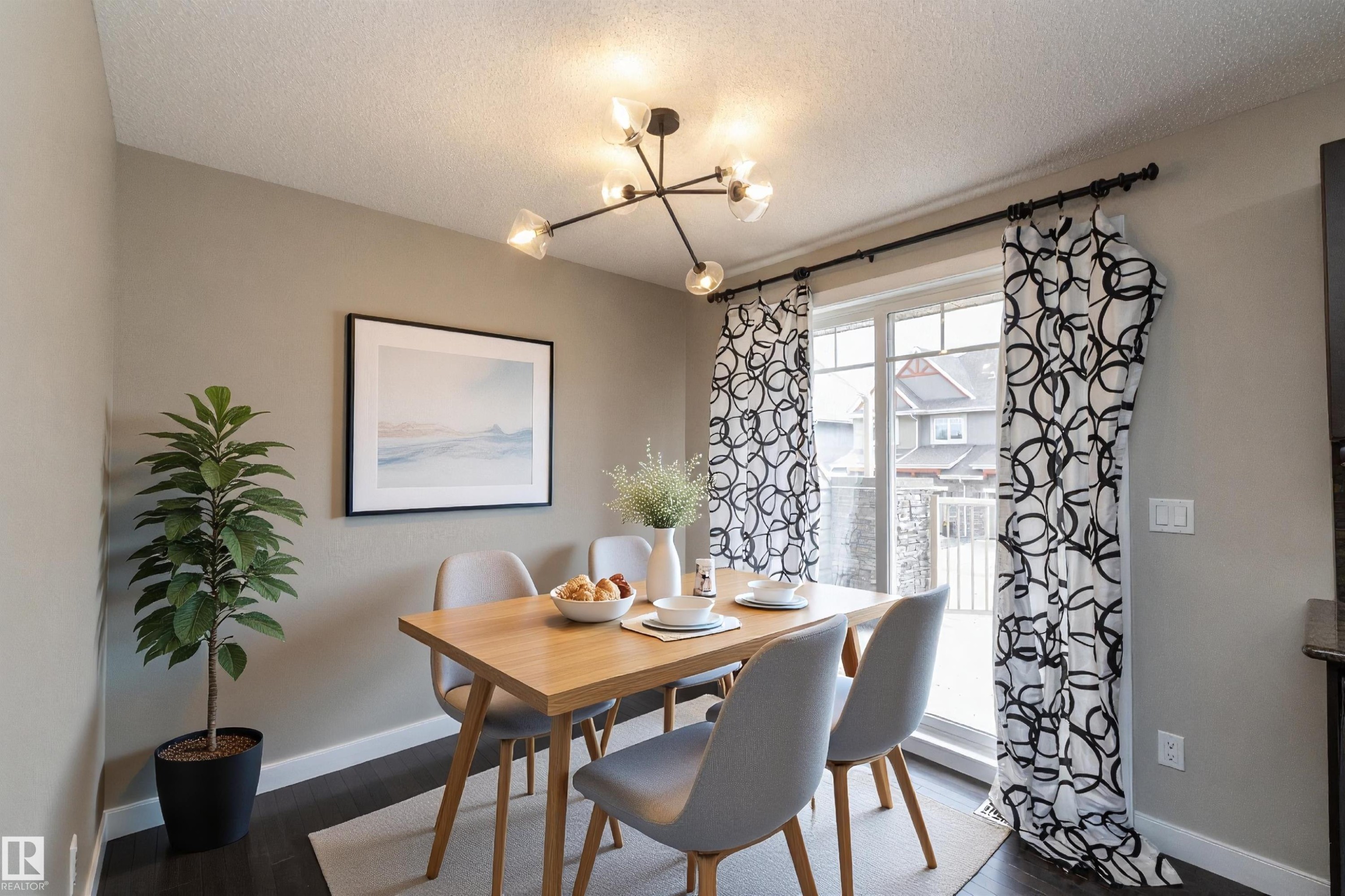 Dining area featuring a modern linear chandelier, dark wood-finish flooring, and a sliding glass door - 117 Callaghan Drive Sw, Edmonton, AB - Indoor Photo Showing Dining Room