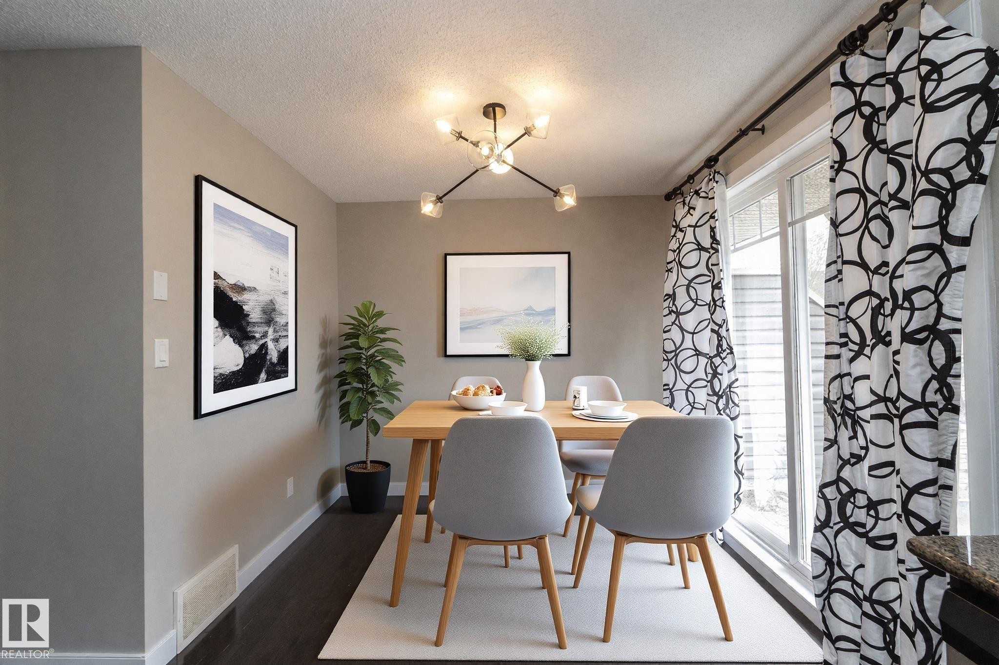 Dining area featuring wood-finish flooring, a contemporary ceiling light fixture, a large patio door, and neutral-toned walls - 117 Callaghan Drive Sw, Edmonton, AB - Indoor Photo Showing Dining Room