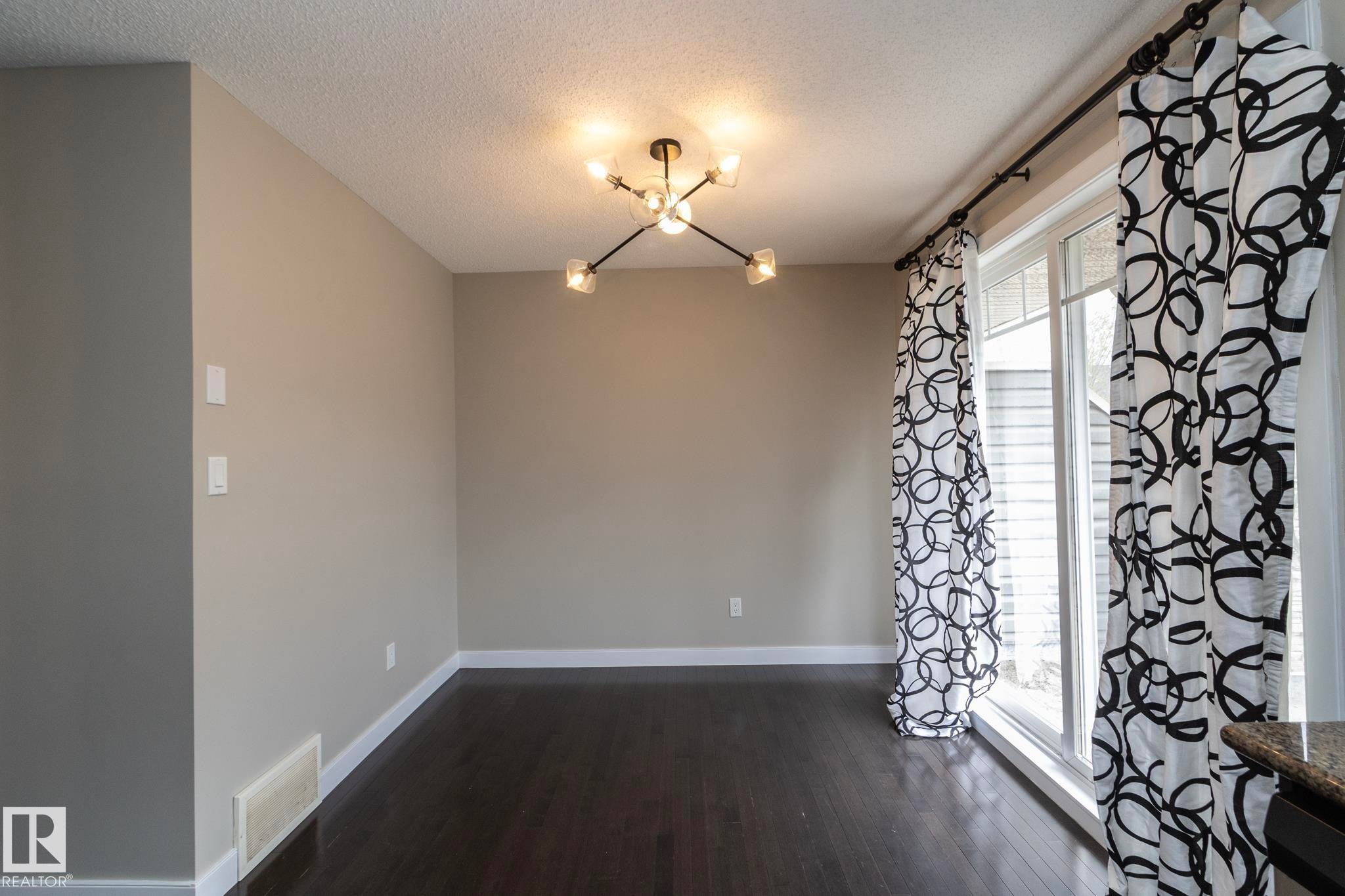 Dark wood-finish flooring complements light neutral wall tones - 117 Callaghan Drive Sw, Edmonton, AB - Indoor Photo Showing Other Room