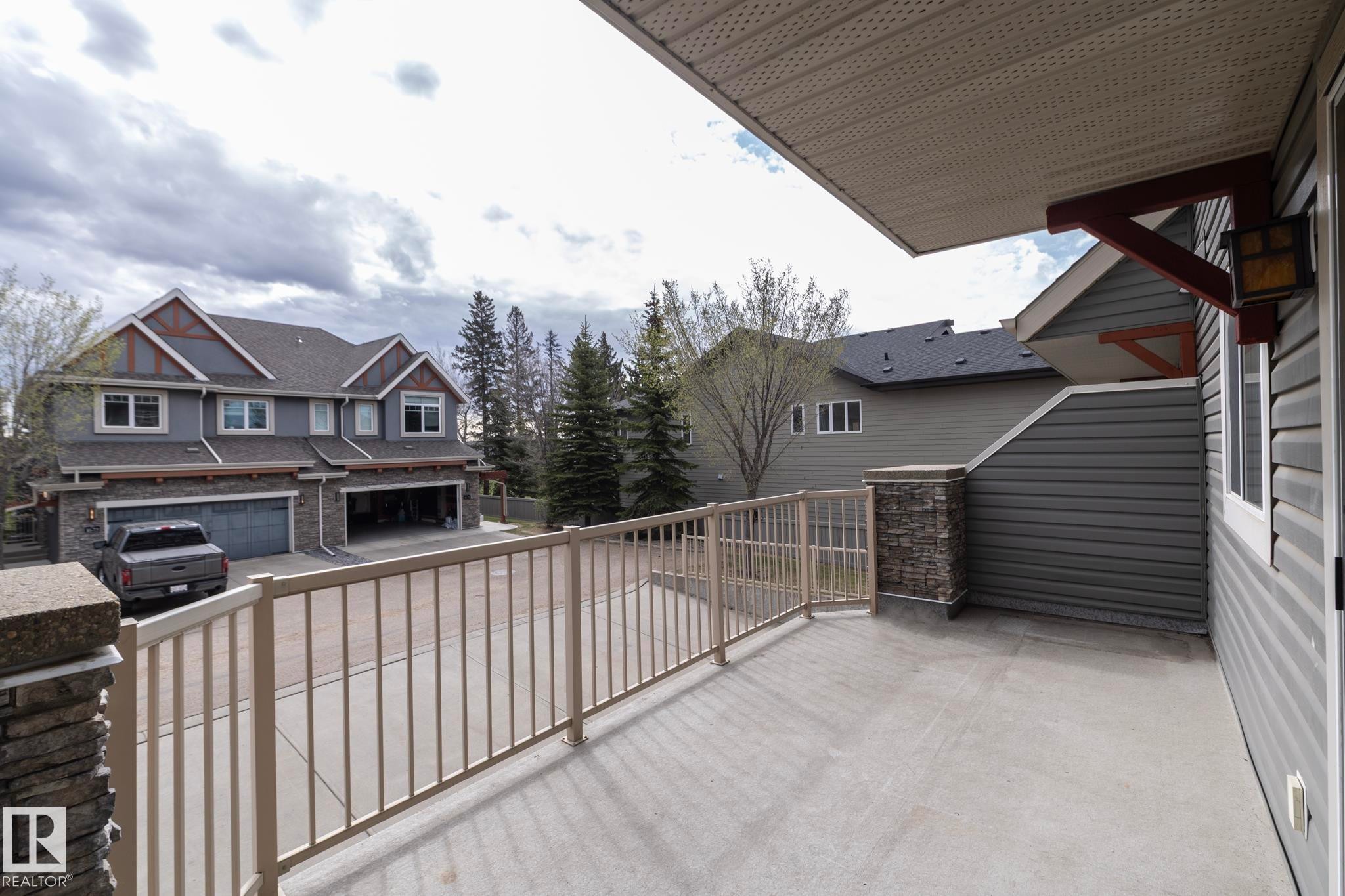 Expansive concrete balcony with metal railings and stone-clad pillars - 117 Callaghan Drive Sw, Edmonton, AB - Outdoor With Exterior