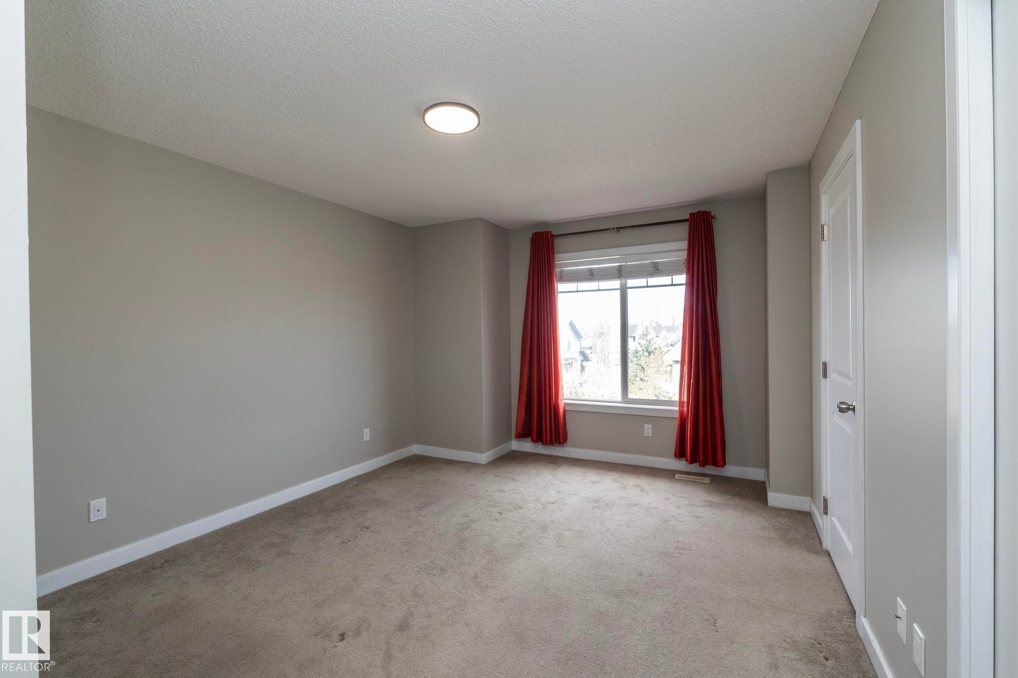 Neutral-toned walls and plush carpeting with white trim and a white two-panel door - 117 Callaghan Drive Sw, Edmonton, AB - Indoor Photo Showing Other Room