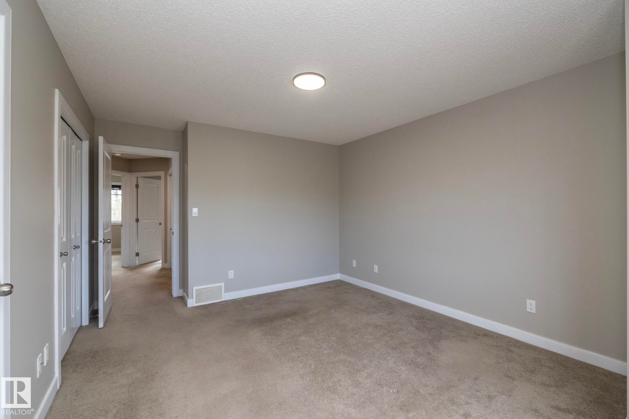Carpeted room with neutral gray walls, white baseboards, and a flush-mount ceiling light fixture - 117 Callaghan Drive Sw, Edmonton, AB - Indoor Photo Showing Other Room