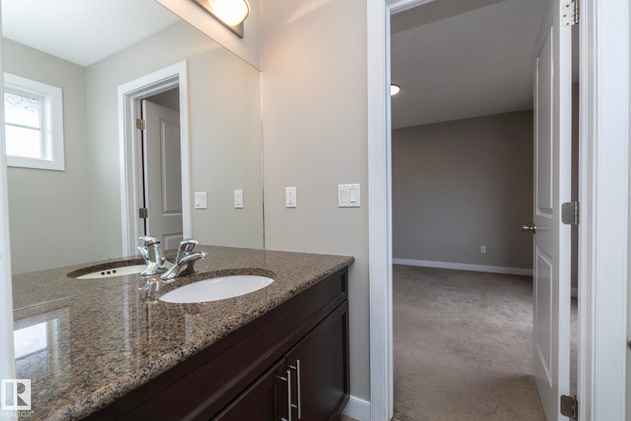 Double vanity featuring a speckled countertop and two undermount sinks with chrome fixtures - 117 Callaghan Drive Sw, Edmonton, AB - Indoor Photo Showing Bathroom